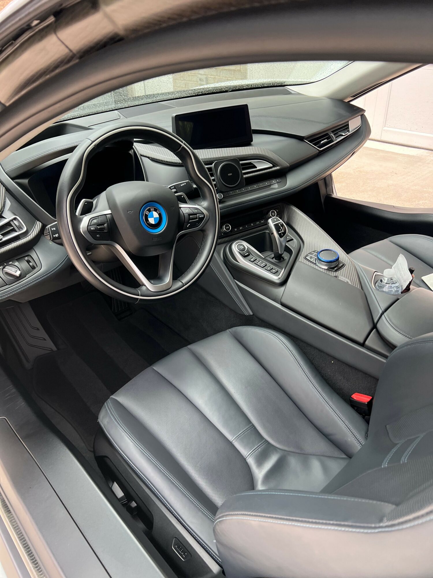 Car interior with steering wheel, dashboard, gear shift, and front seat visible.