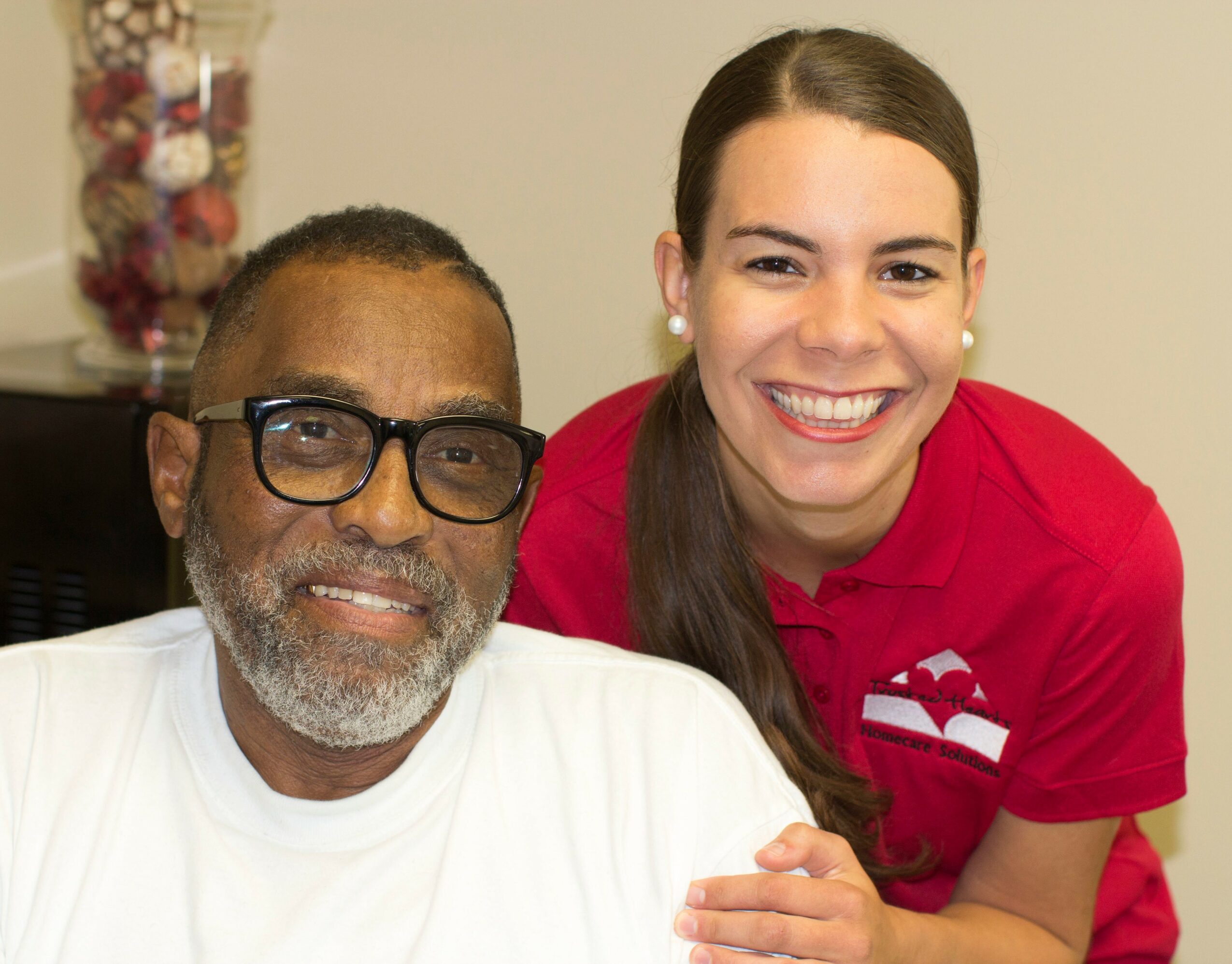 A smiling woman with long dark hair and a man with glasses and a beard pose together indoors.