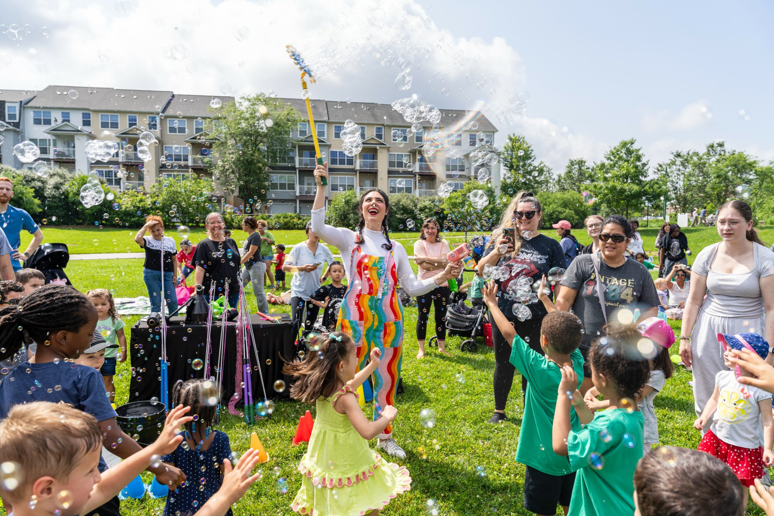 People celebrating outdoors with water activities, children playing, and a woman in a colorful dress holding a flag.