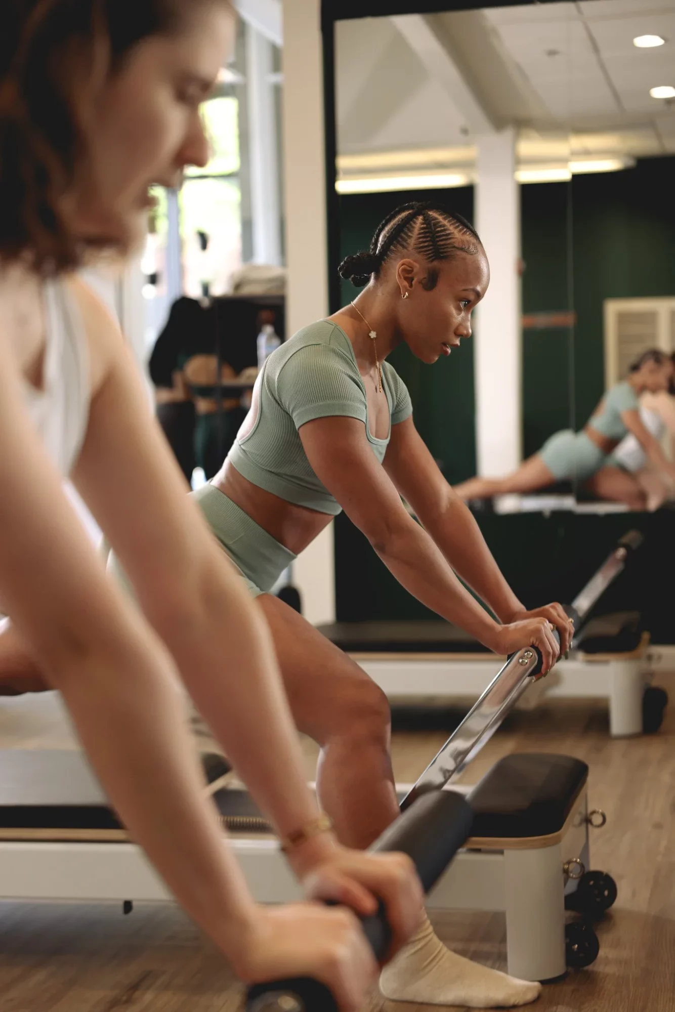 Two women exercising on rowing machines in a gym, focused on workout.