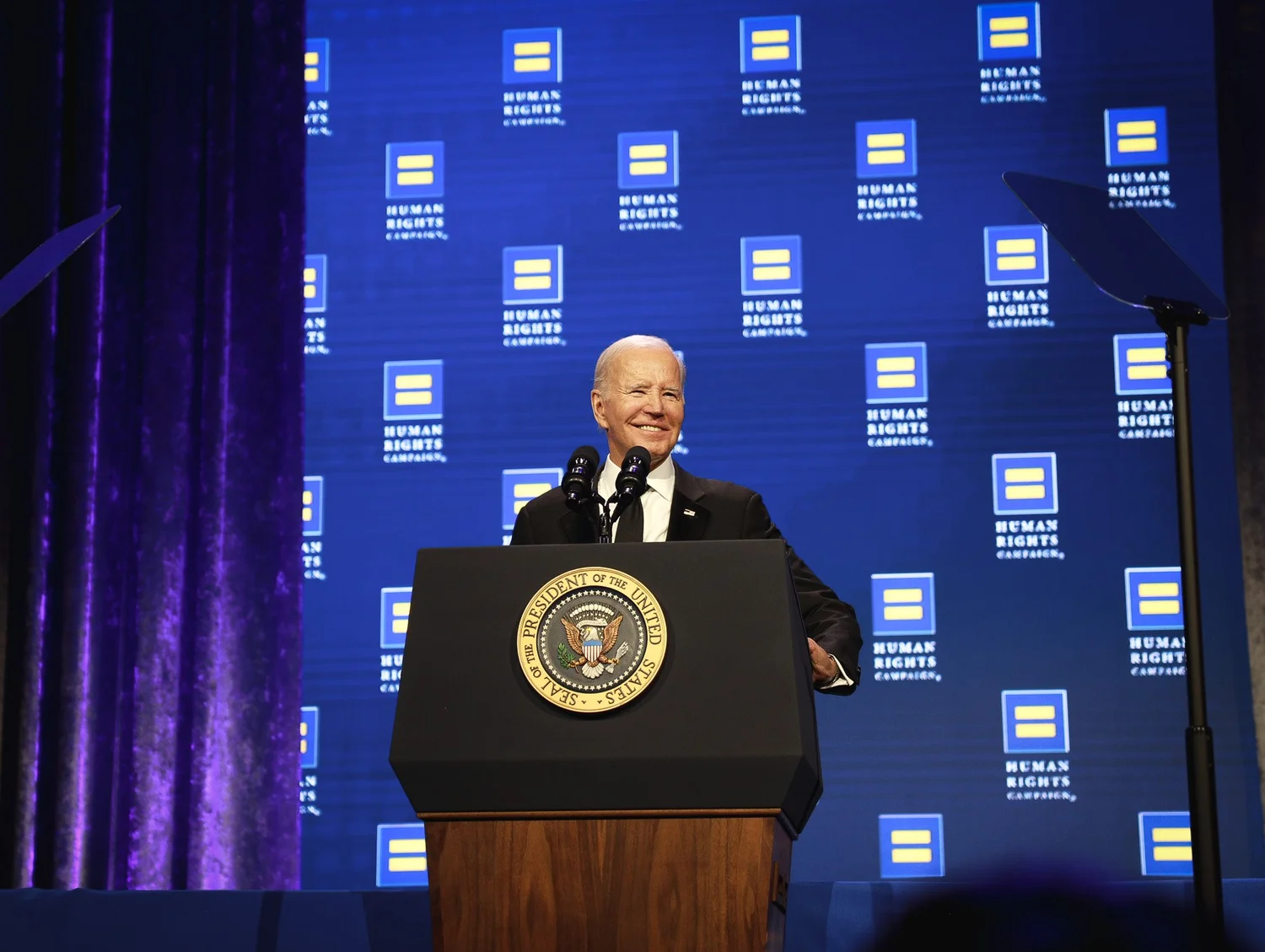 President Biden speaking at a podium with the presidential seal, in front of a blue background with Human Rights Campaign logos.