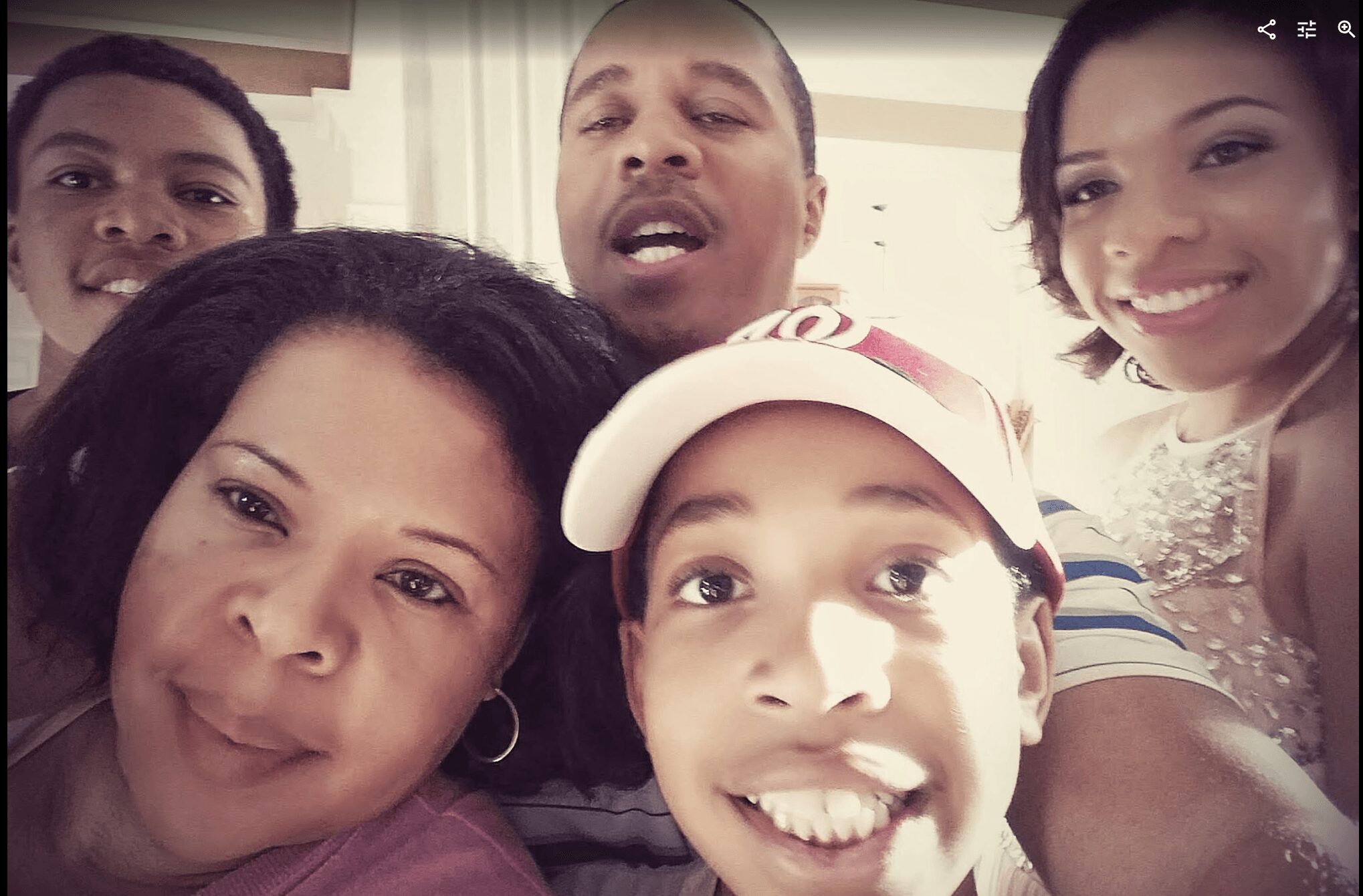 Group of five people smiling and taking a selfie indoors.