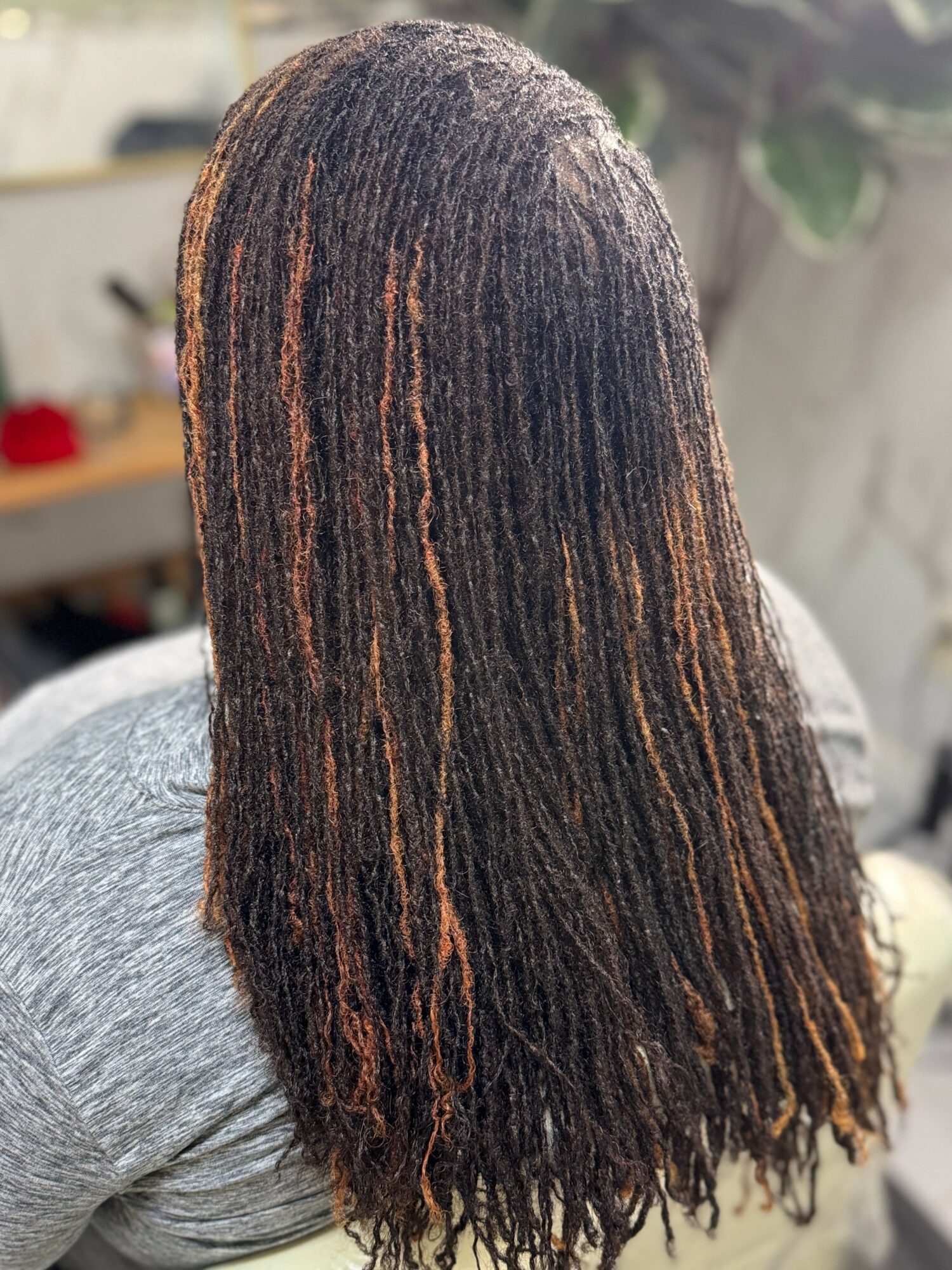 Back of a person's head with long, textured, dark hair with light brown highlights.