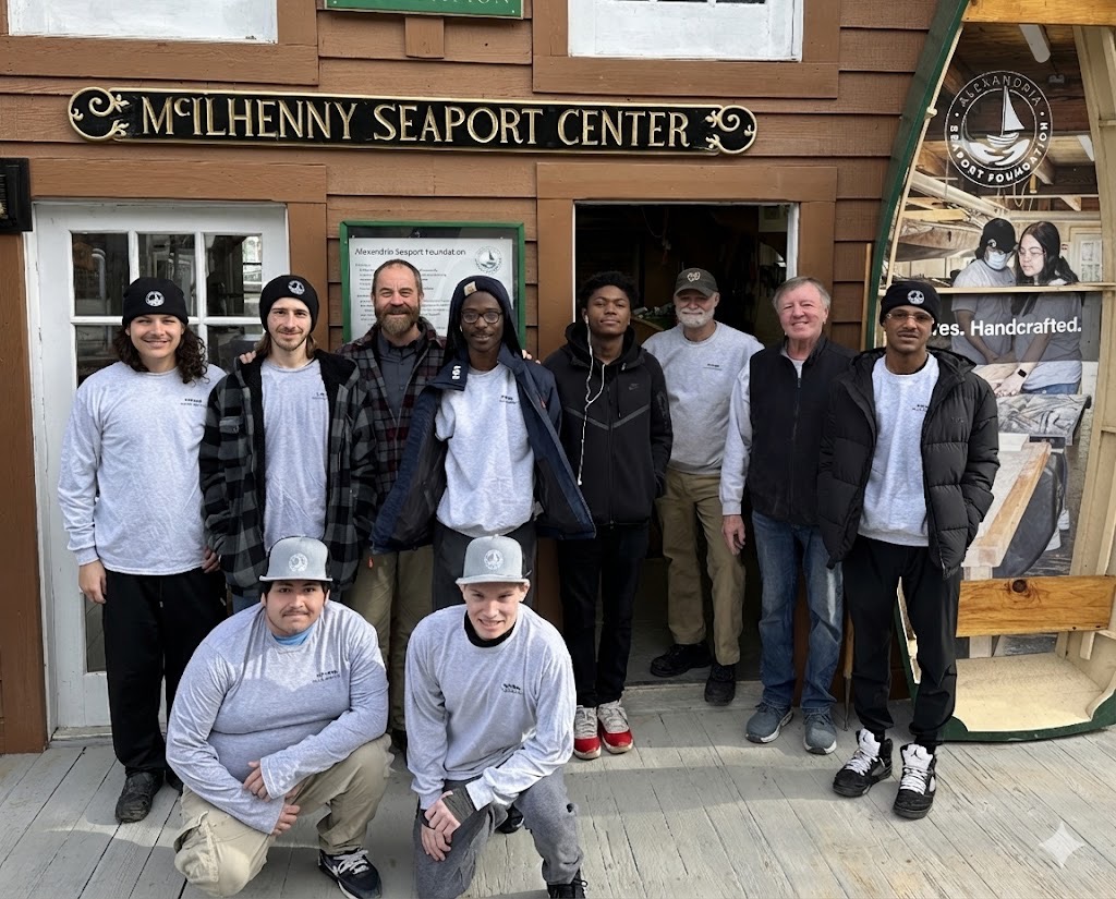Group of ten people standing outside a building with a sign reading 'Milhenny Seaport Center'.