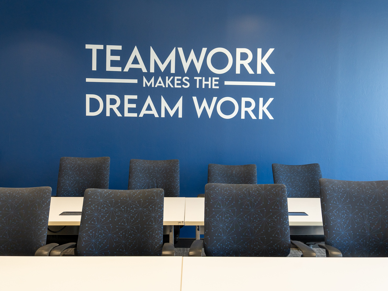 Conference room with chairs and a wall with motivational quote about teamwork and dream work.