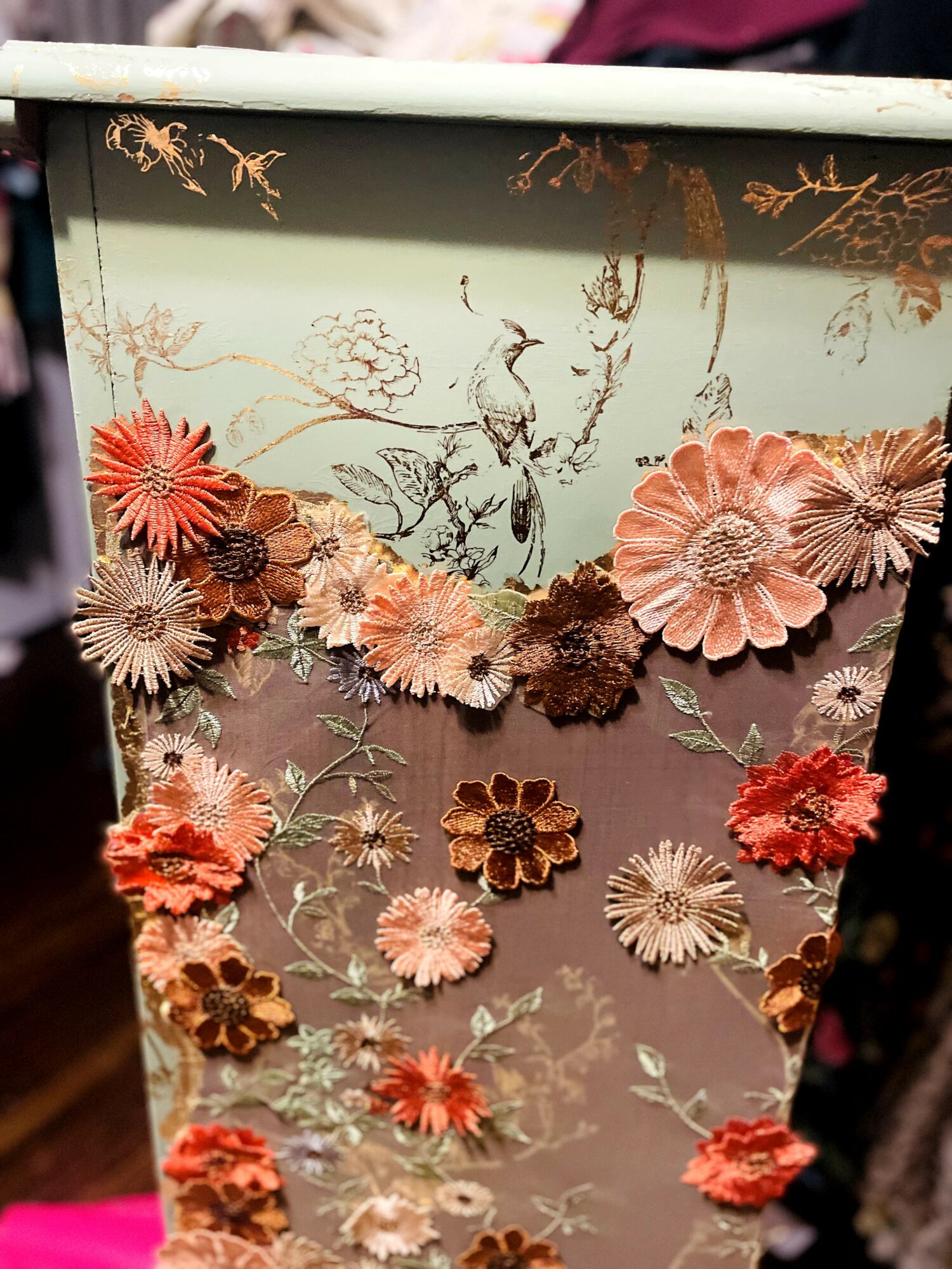 Decorative container with floral and botanical patterns, featuring pink, beige, and brown flowers and leaves.