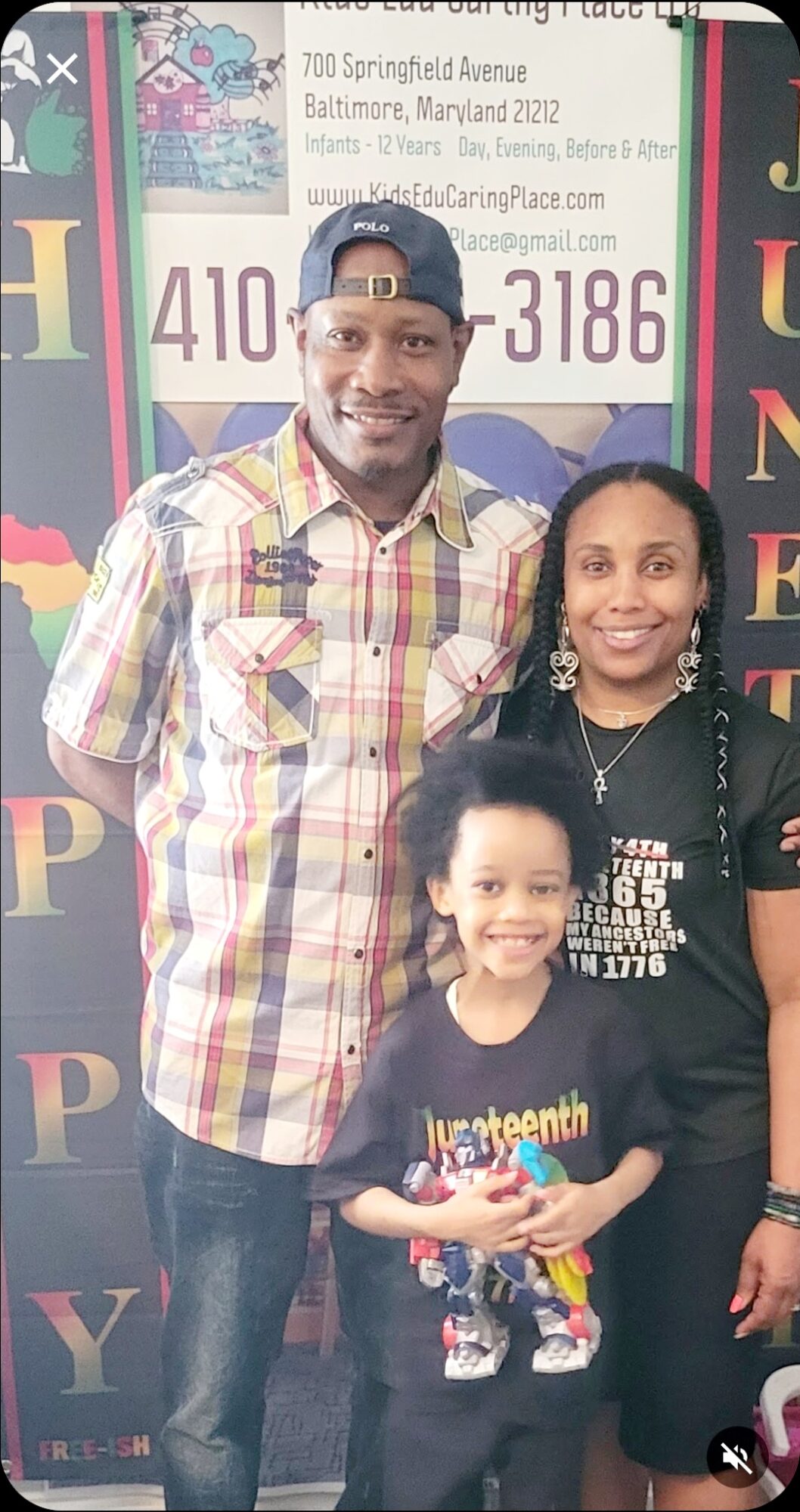 Three people smiling, standing indoors in front of a colorful background with text and numbers.