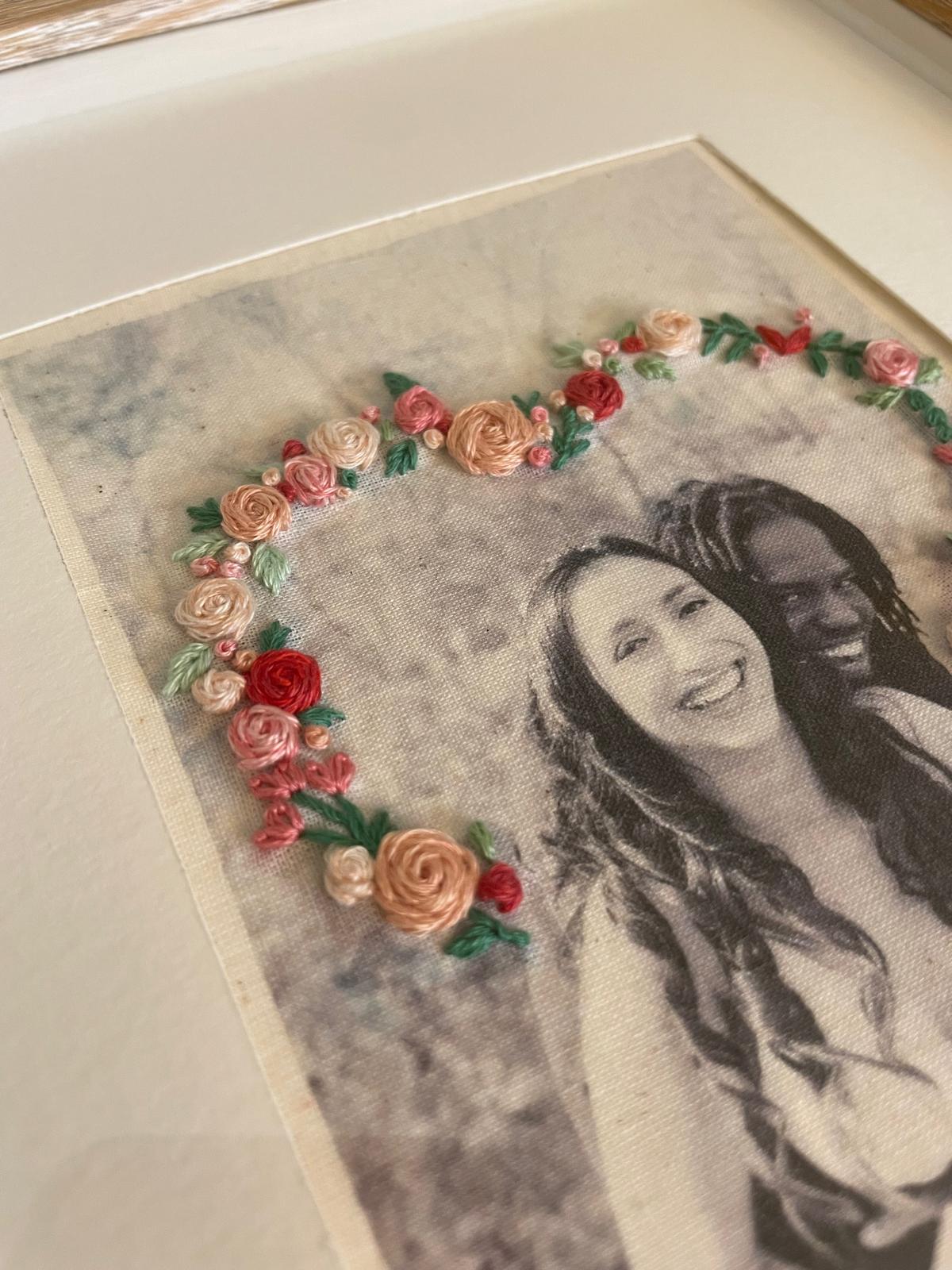 Black and white photo of two smiling women with a floral heart-shaped decoration above them.