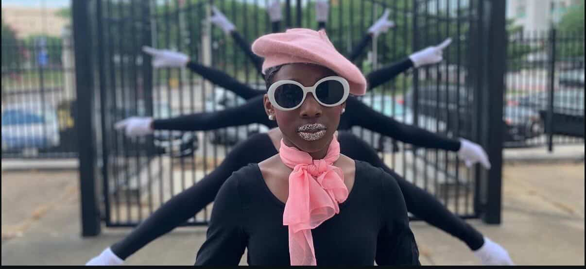 Person wearing pink hat, sunglasses, pink scarf, and black outfit, with multiple arms extending behind them.