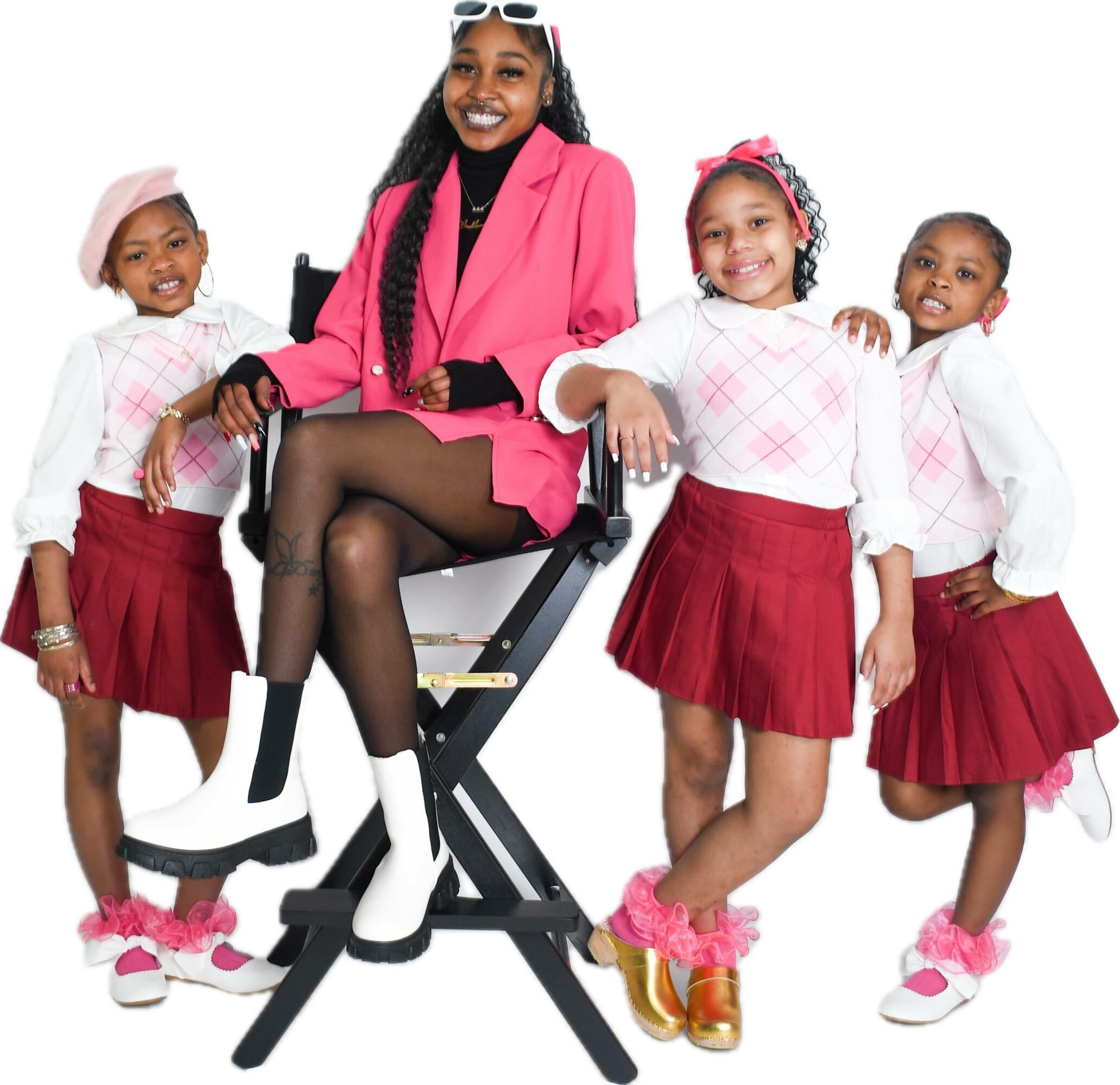 Woman sitting on a chair with four children standing around her, all smiling, against a white background.