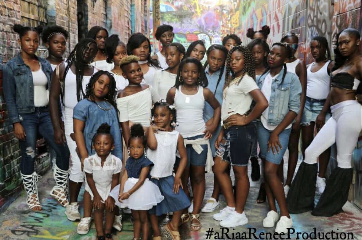 Group of children and teenagers standing in a colorful outdoor urban setting with graffiti walls.