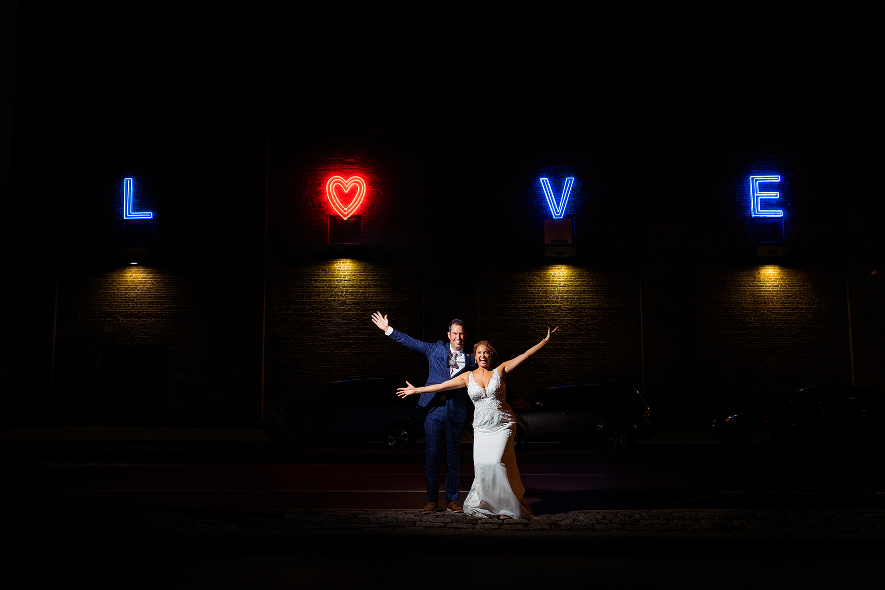 Couple dancing in front of illuminated letters spelling LOVE, with a heart symbol above the letter O.