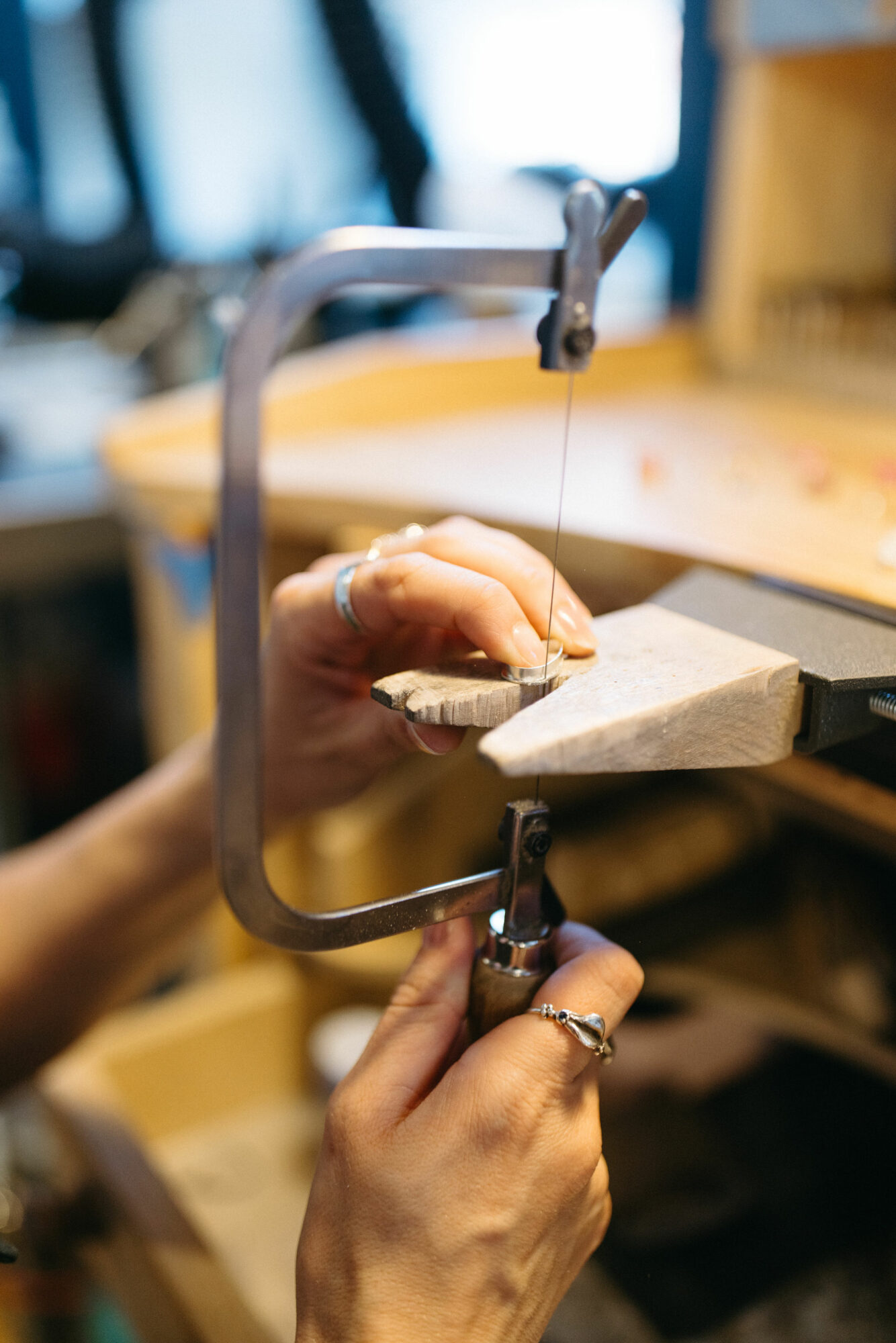 Person's hands using a saw to cut a piece of wood in a workshop.