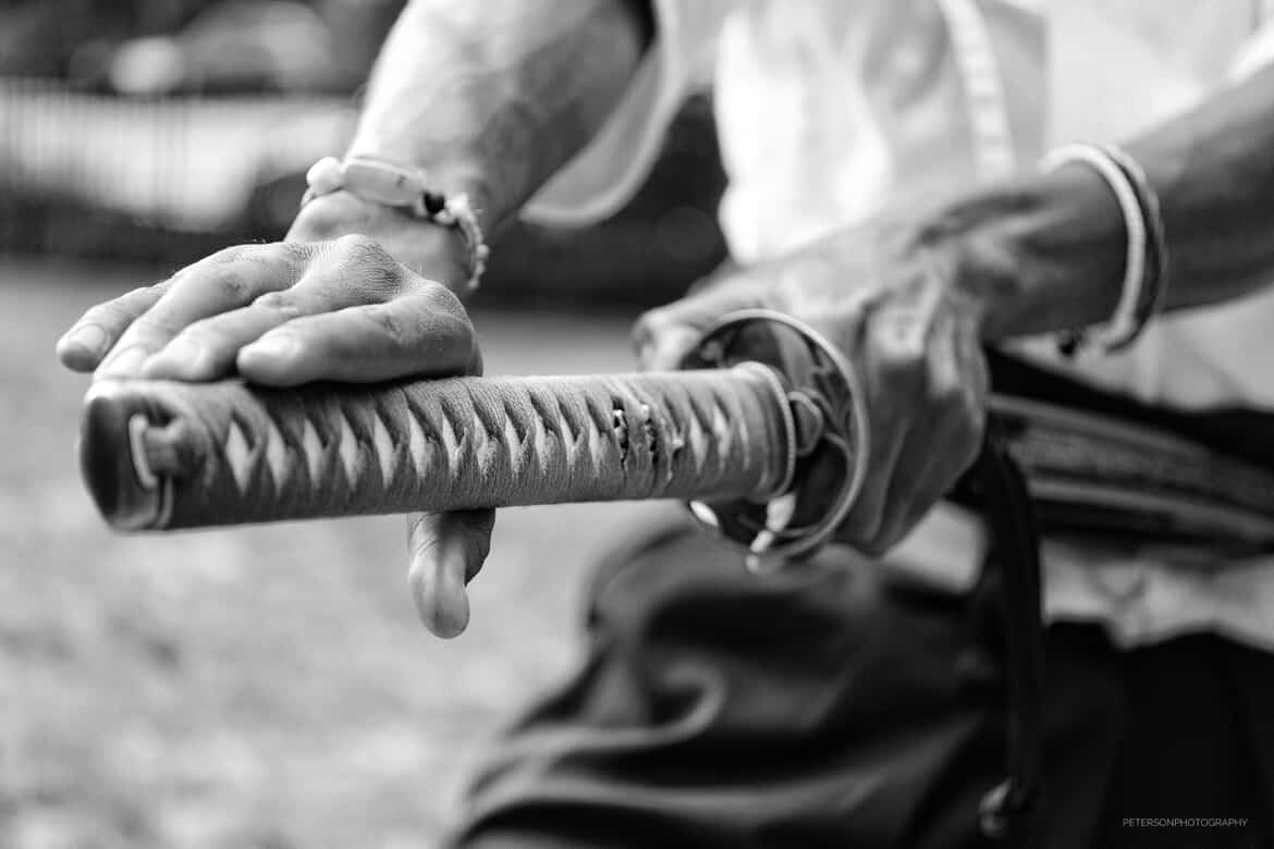 Close-up of a person gripping a textured baseball bat with both hands, black and white image.