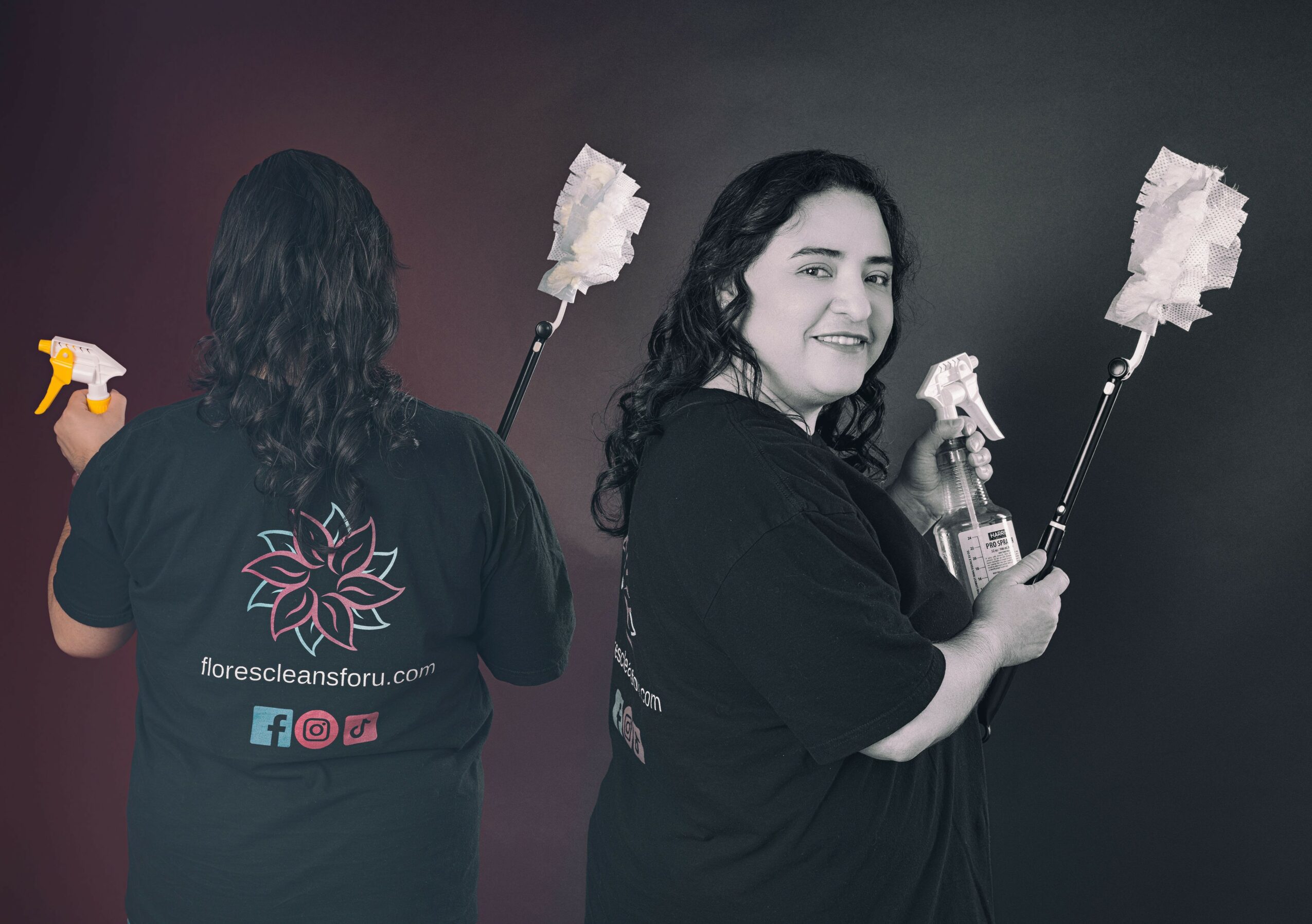 Two women hold cleaning tools, one facing away and one smiling at the camera, against a dark background.