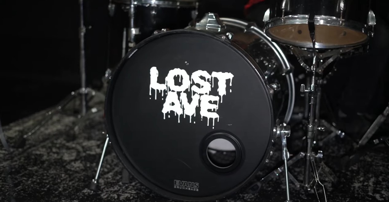 Drum with 'LOST IN THE' text on the front, part of a drum set, on a dark stage.