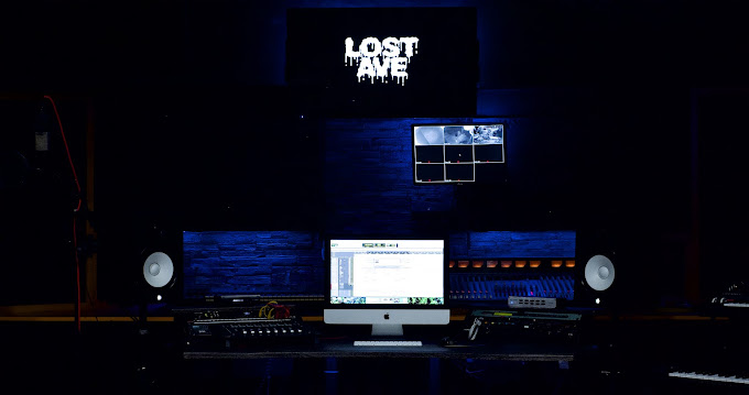 Music studio with computer, speakers, and equipment, and a screen displaying 'Lost Time' in a dark room.