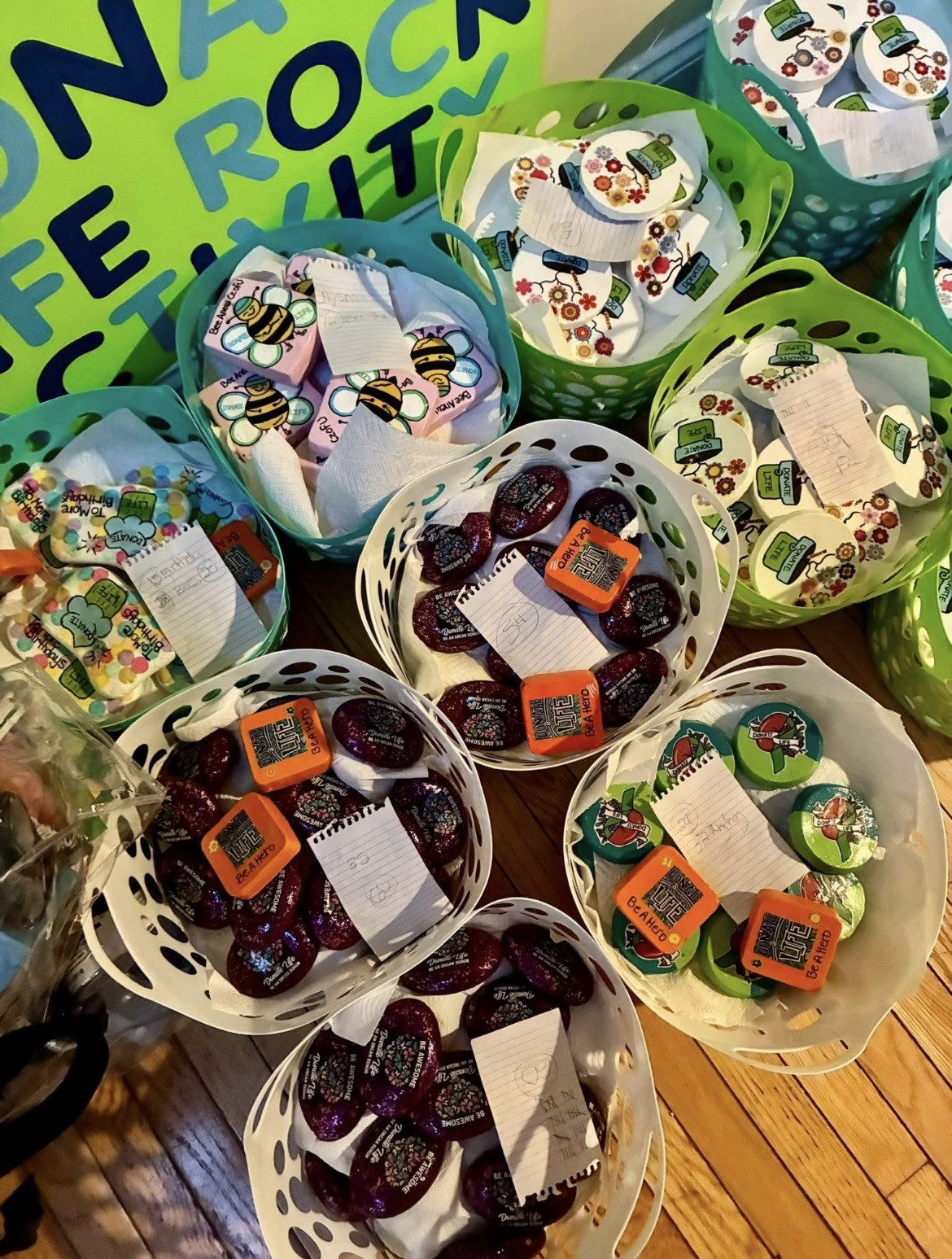 Multiple containers with colorful items inside, placed on a wooden surface, with a green and blue background partially visible.