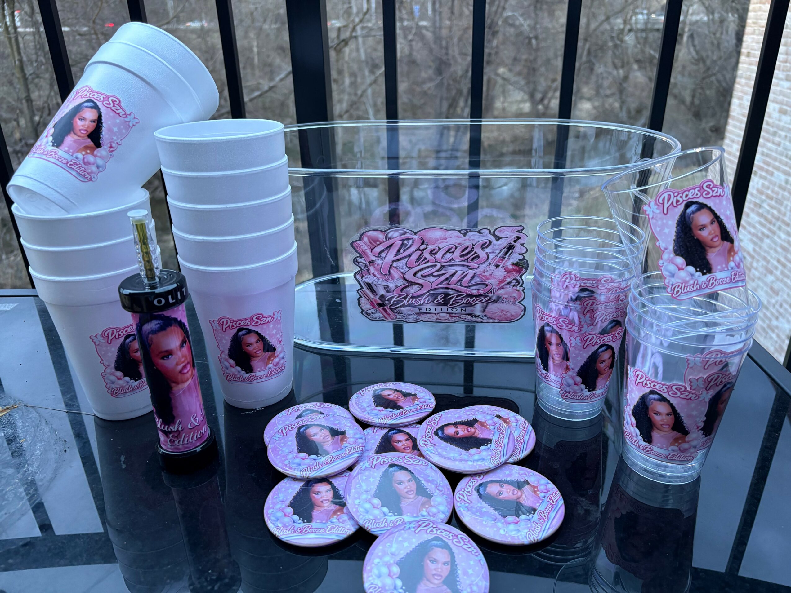 Party supplies with princess theme, including cups, plates, and a clear container, decorated with images of a woman and pink accents.