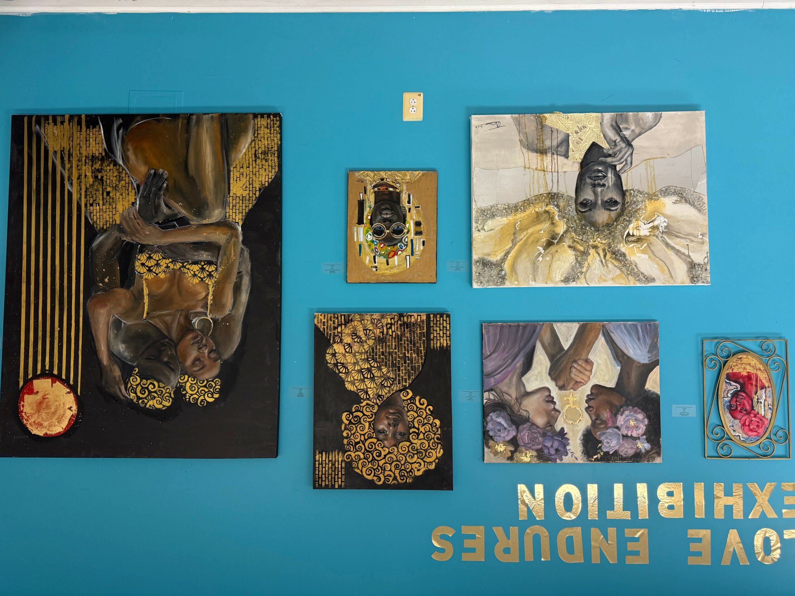 Six framed artworks on a blue wall, including animals and abstract designs, with white text reading 'LOVE ENDEURS EXHIBITION'.