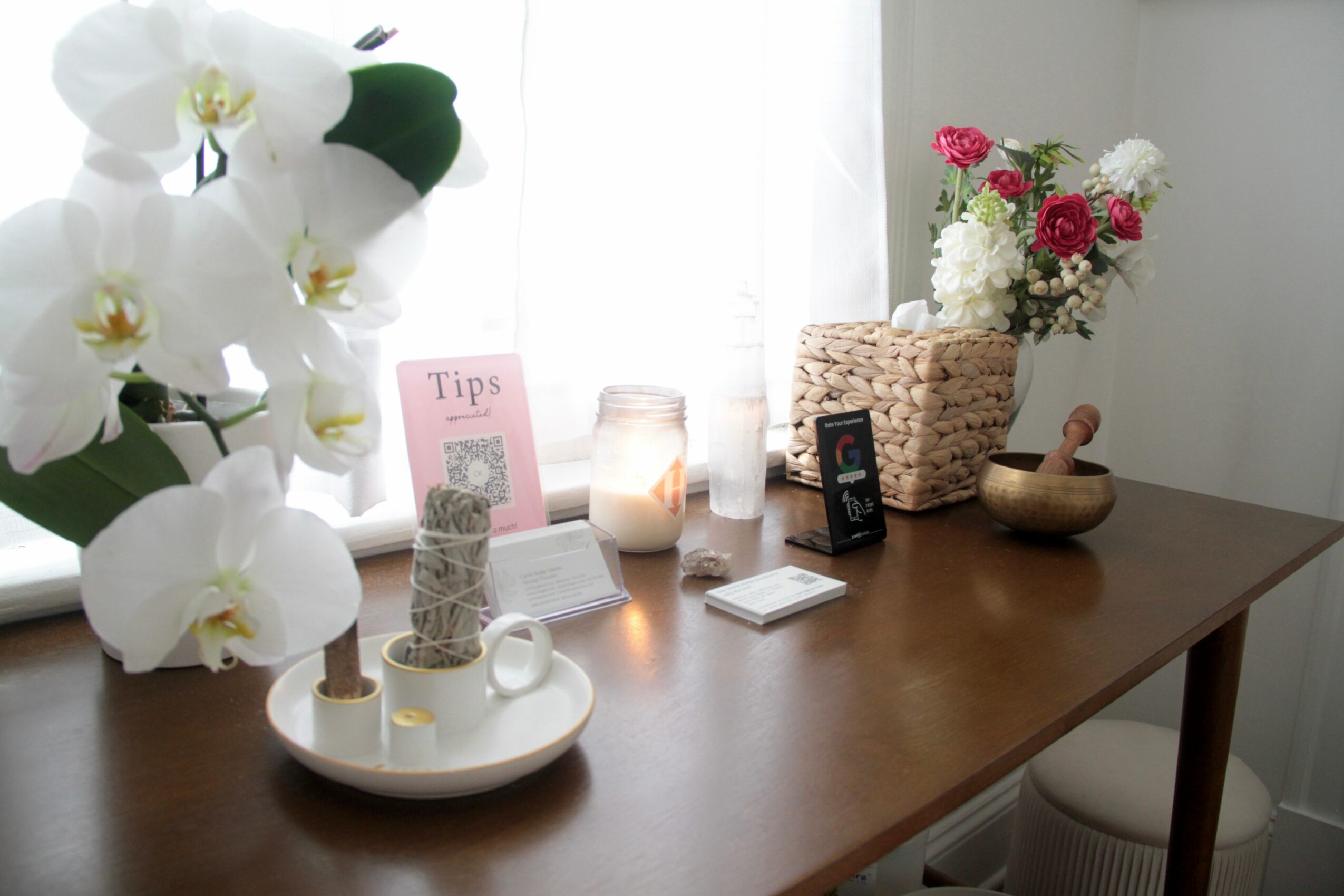 Wooden table with flowers, candles, and decorative items in a bright room.