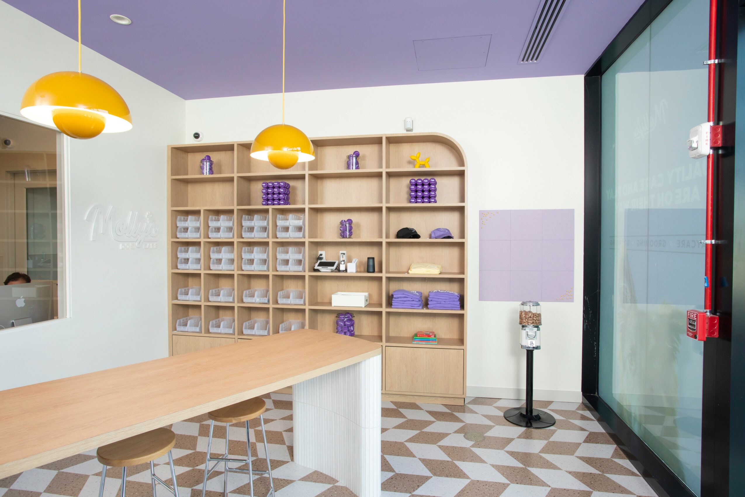 Interior of a modern room with a wooden shelf, purple decor, a large window, and a patterned floor.