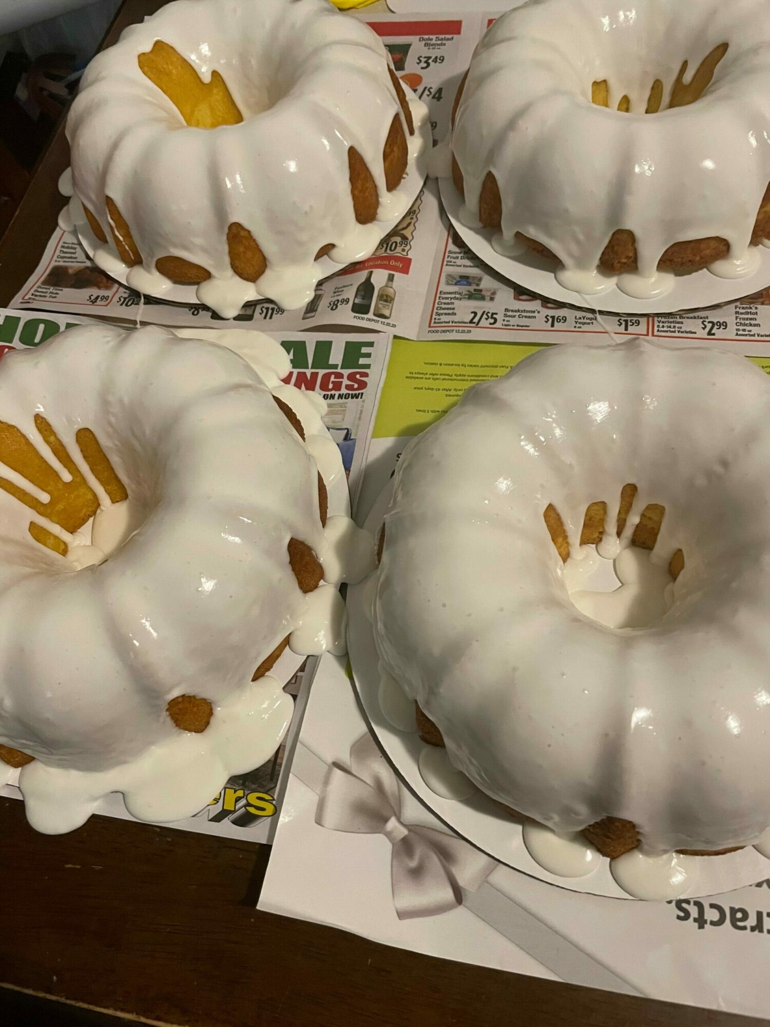 Four white ceramic pumpkin-shaped containers with brown accents, placed on newspapers and papers on a wooden surface.
