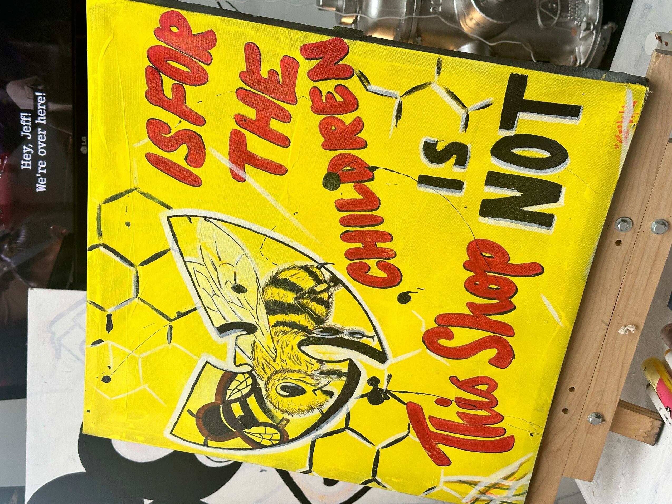 Yellow sign with a bee illustration and red and black text reading 'Is for the children. This shot is not.'