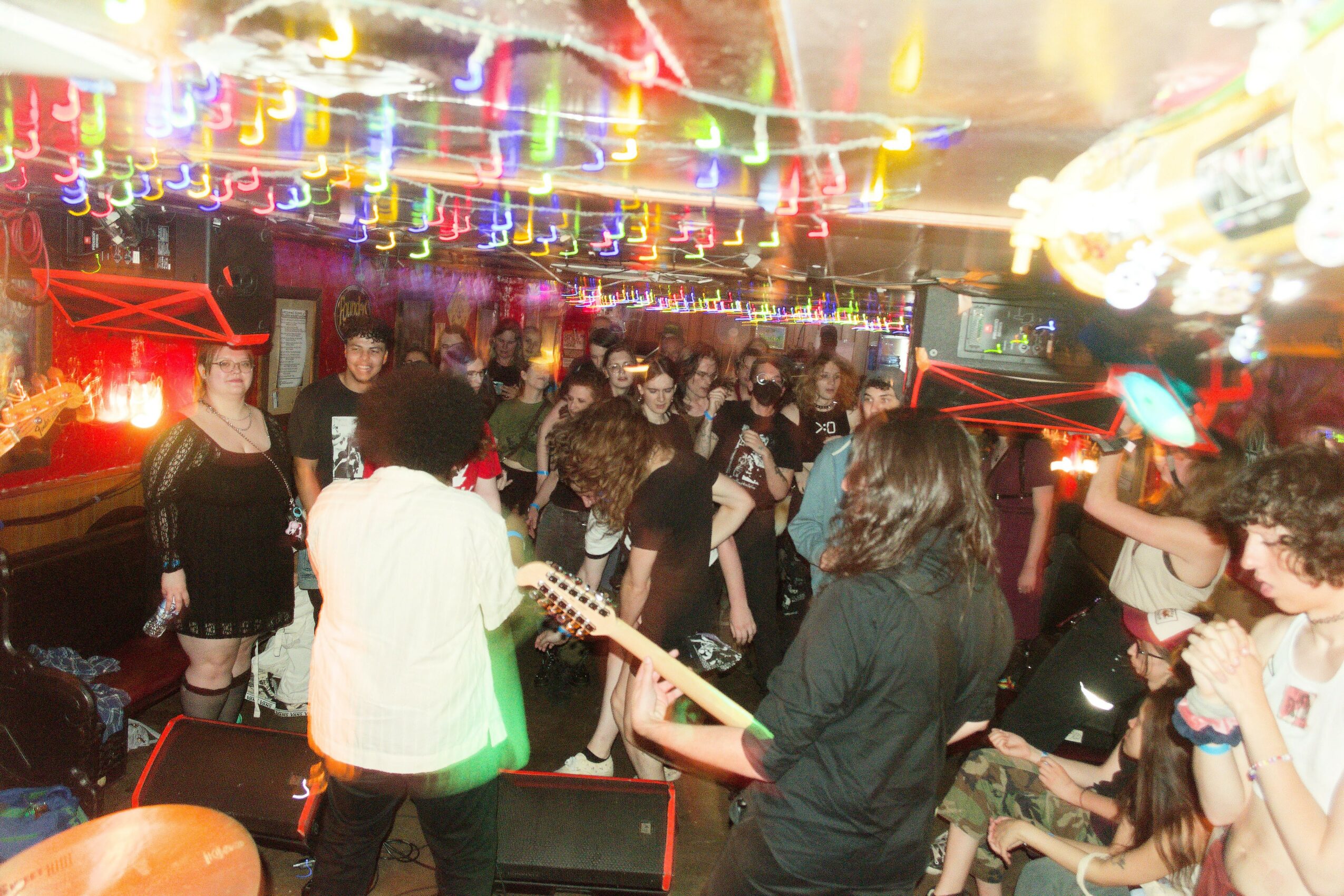 People dancing and socializing in a colorful nightclub with bright lights and a lively atmosphere.