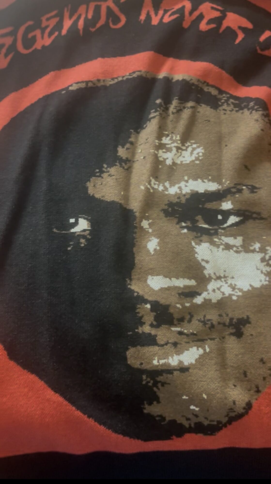 Close-up of a graphic face with intense eyes, partially obscured by a circular design, on a red background.
