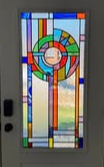 Colorful stained glass window with geometric patterns and a landscape scene at the bottom.