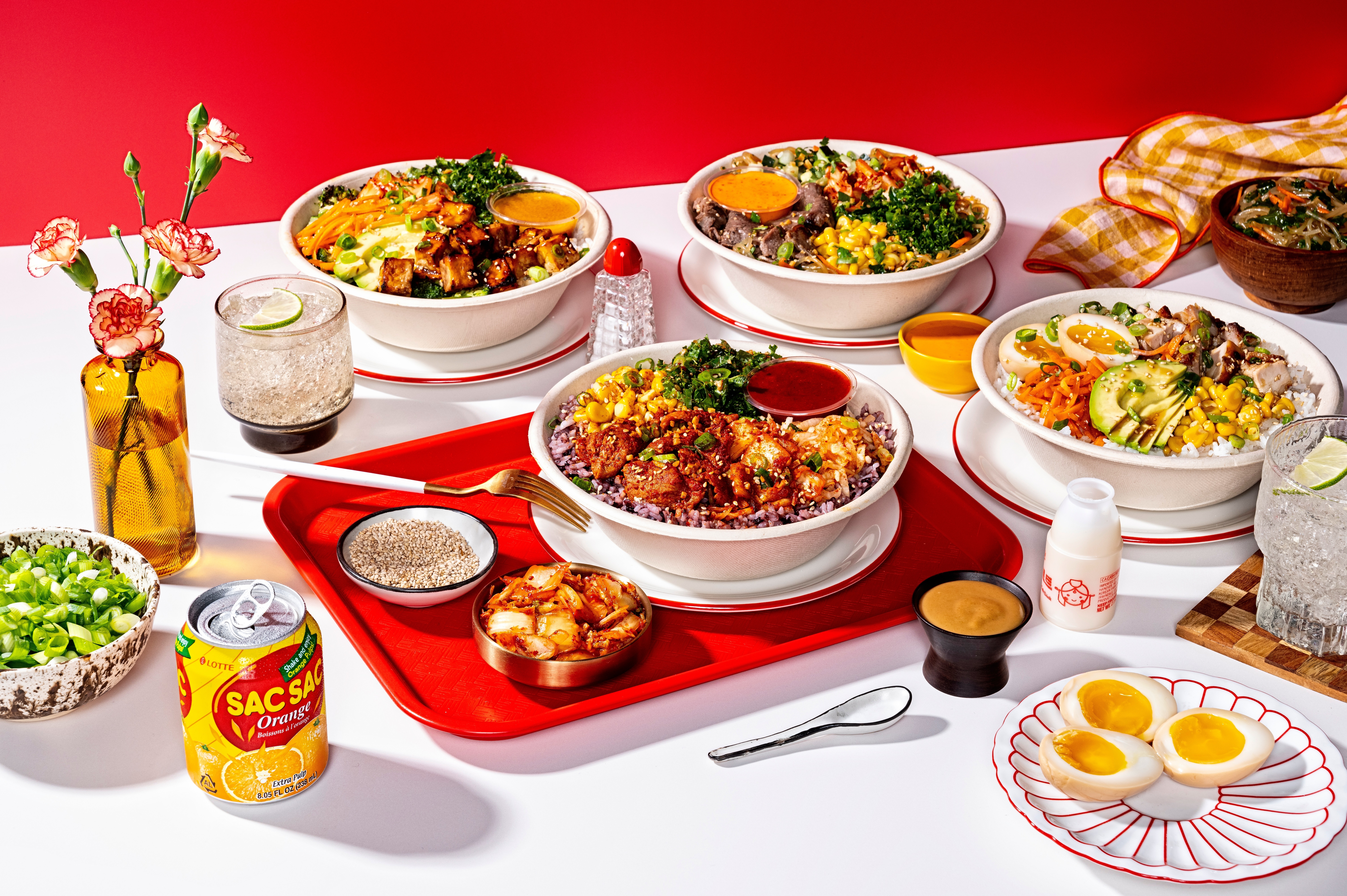 Table with various dishes including salads, eggs, and beverages, set against a red background.