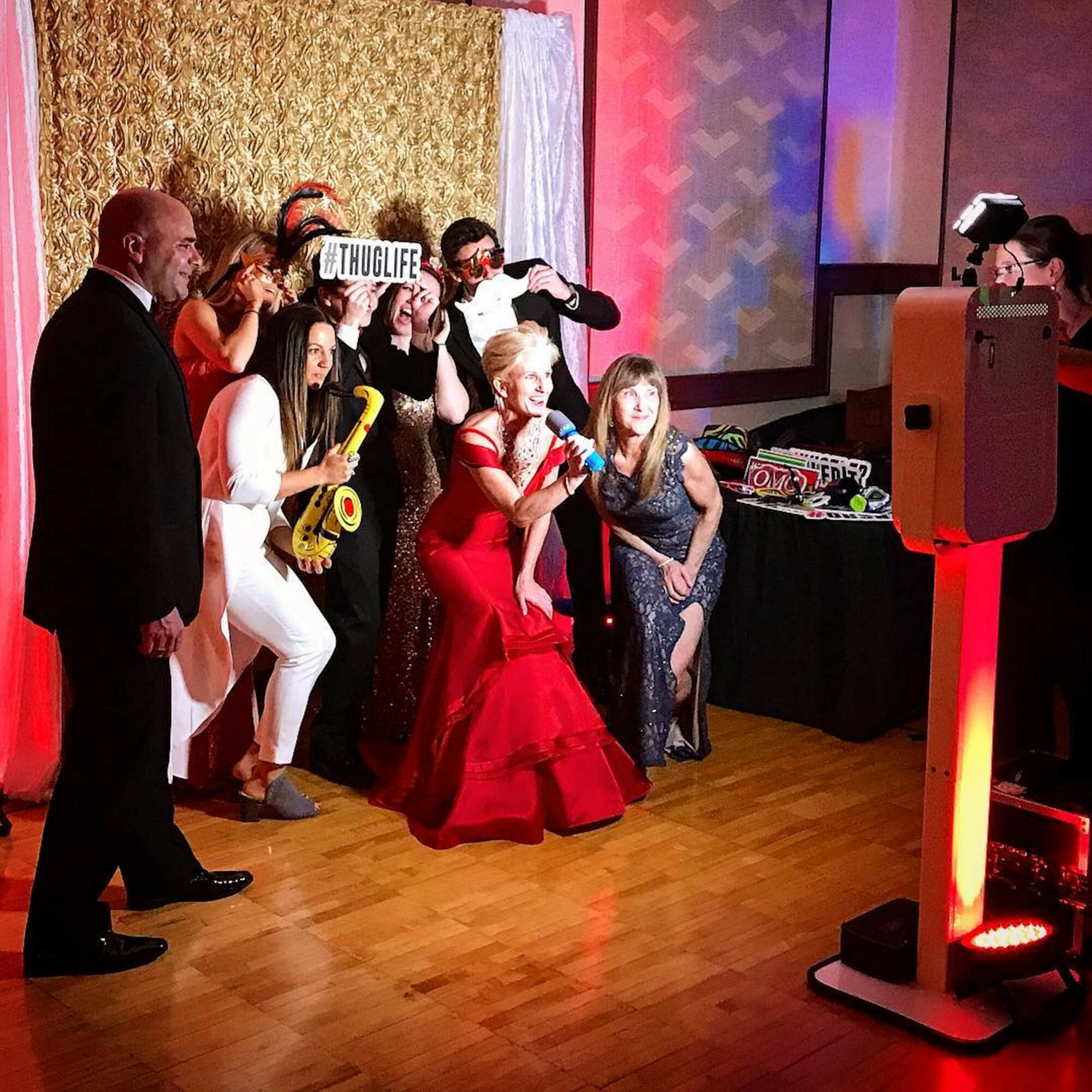 Group of people dancing and singing at a party with a DJ and colorful decorations.