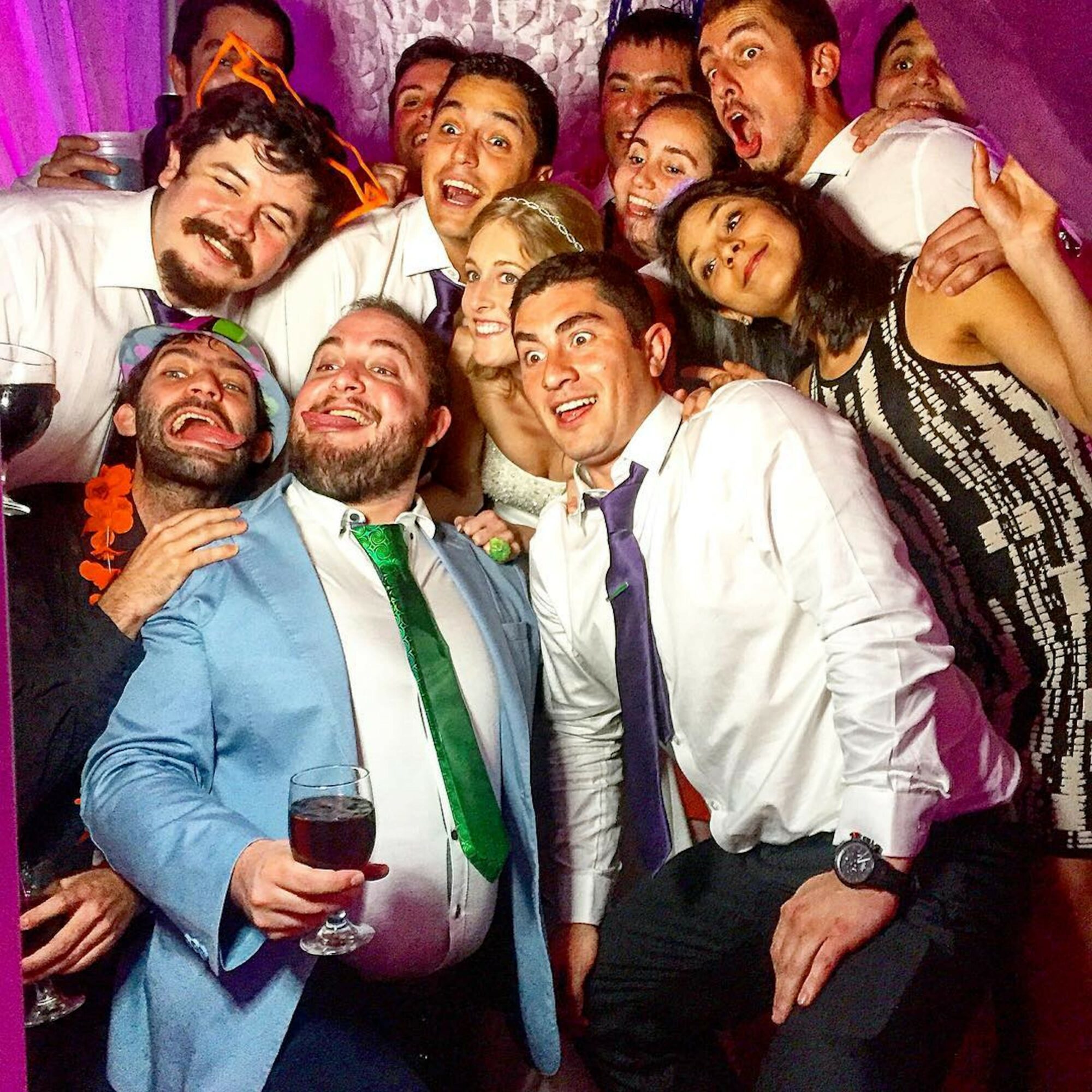 Group of people celebrating, smiling, and posing together at a party with colorful background.