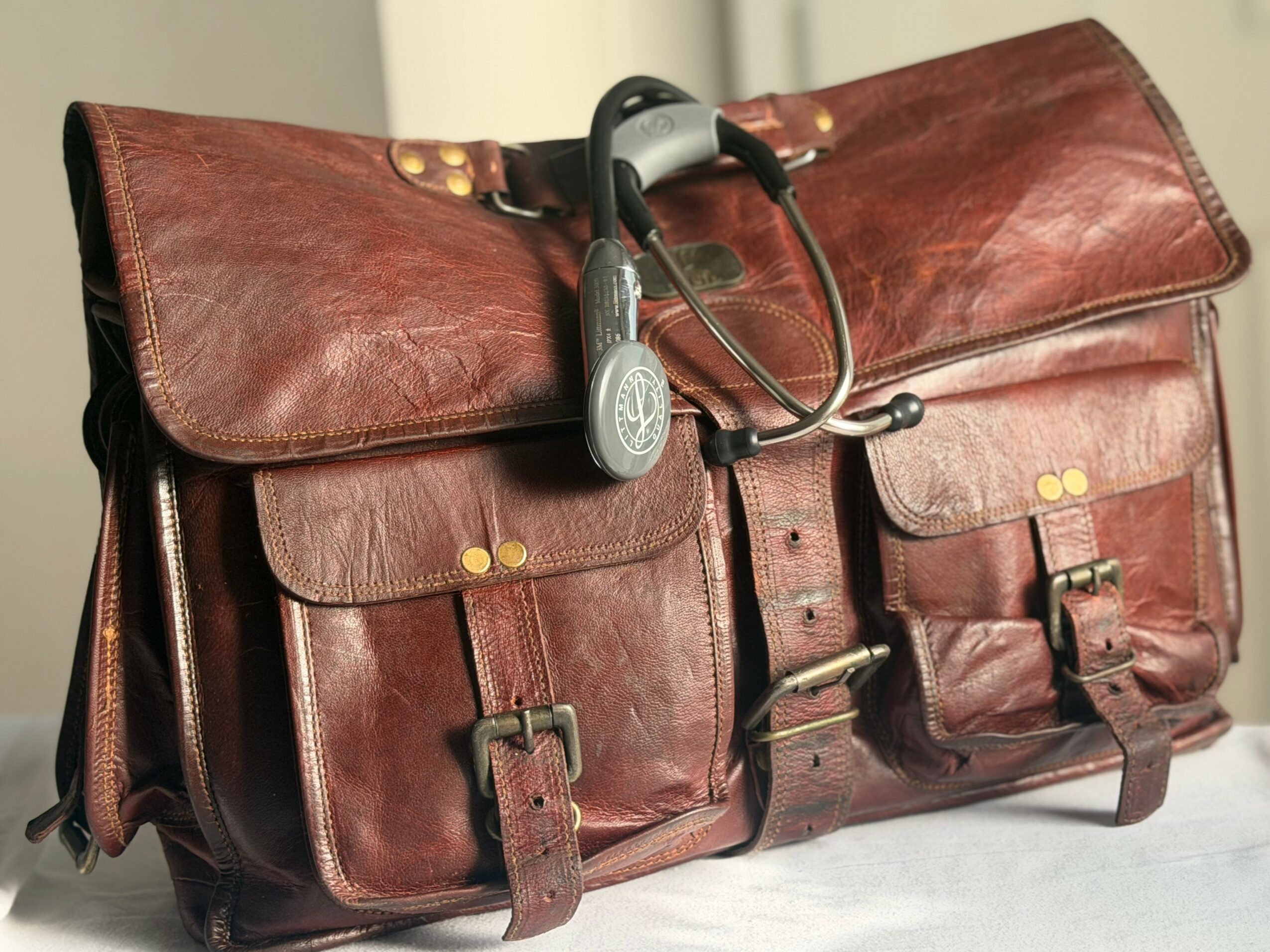 Brown leather bag with multiple pockets and buckles, with headphones resting on top.
