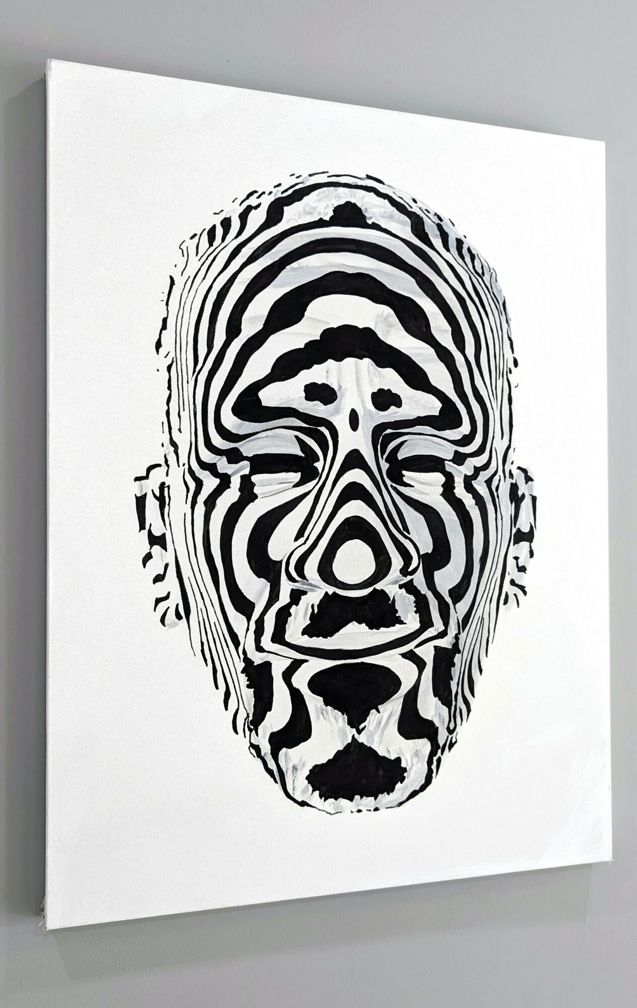 Black and white abstract face with concentric patterns, symmetrical, on a white background.