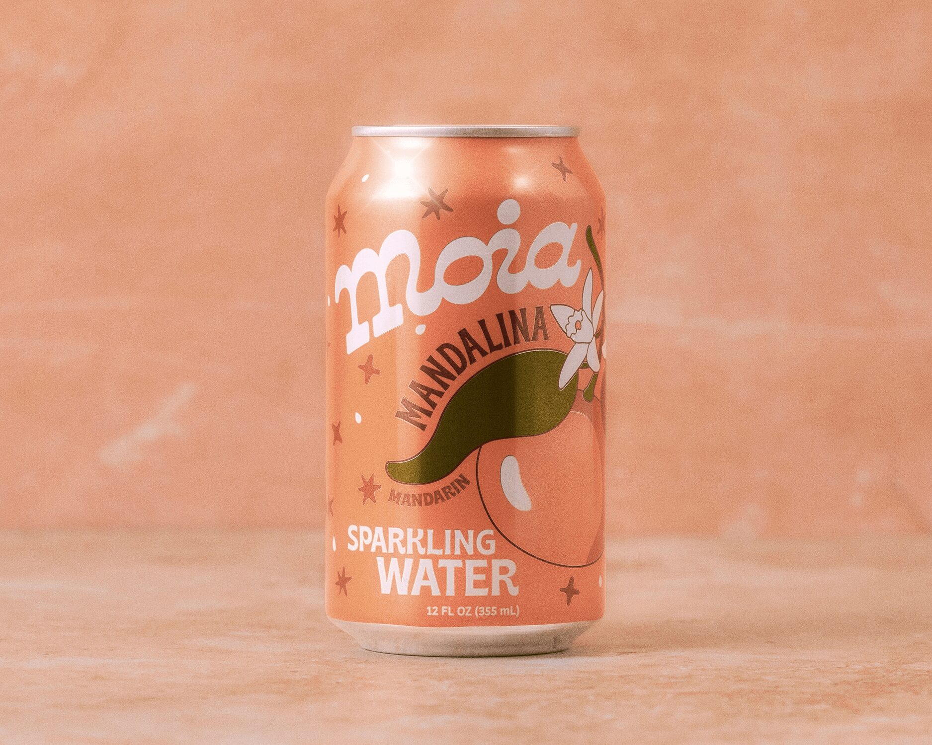 A can of Moia Mandalina sparkling water on a wooden surface with a pink background.