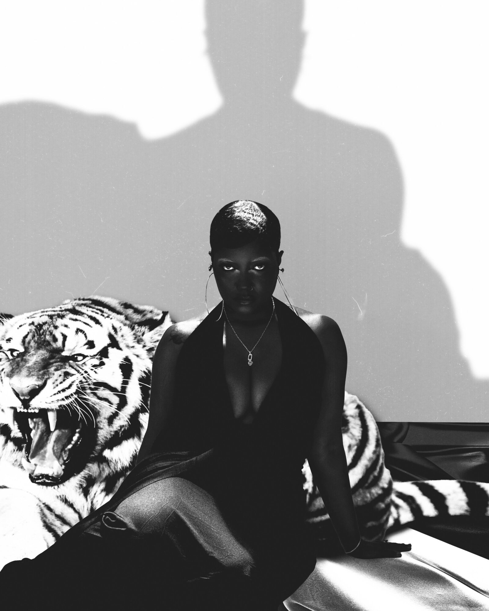 Woman sitting on a tiger-patterned couch with a large shadow behind her, in black and white.