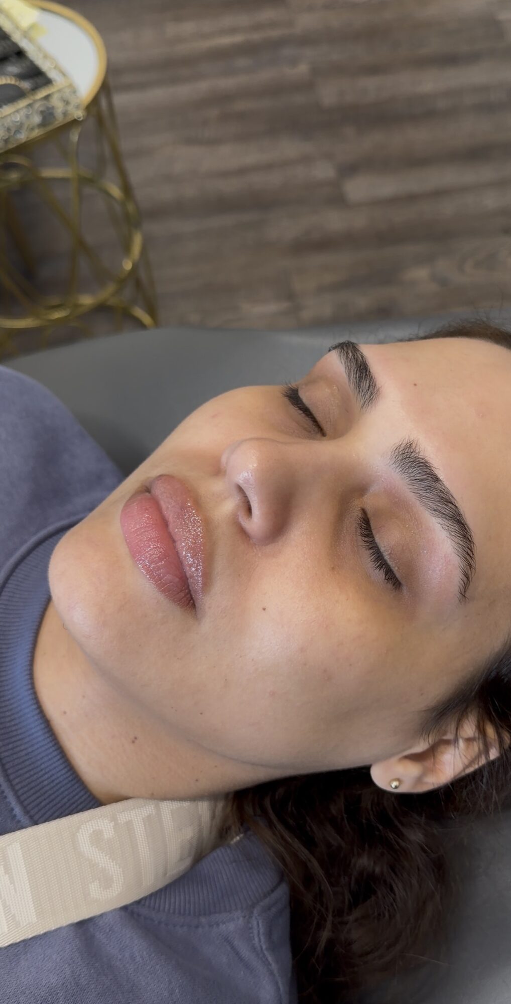 Close-up of a woman with closed eyes, lying down with a neutral background.