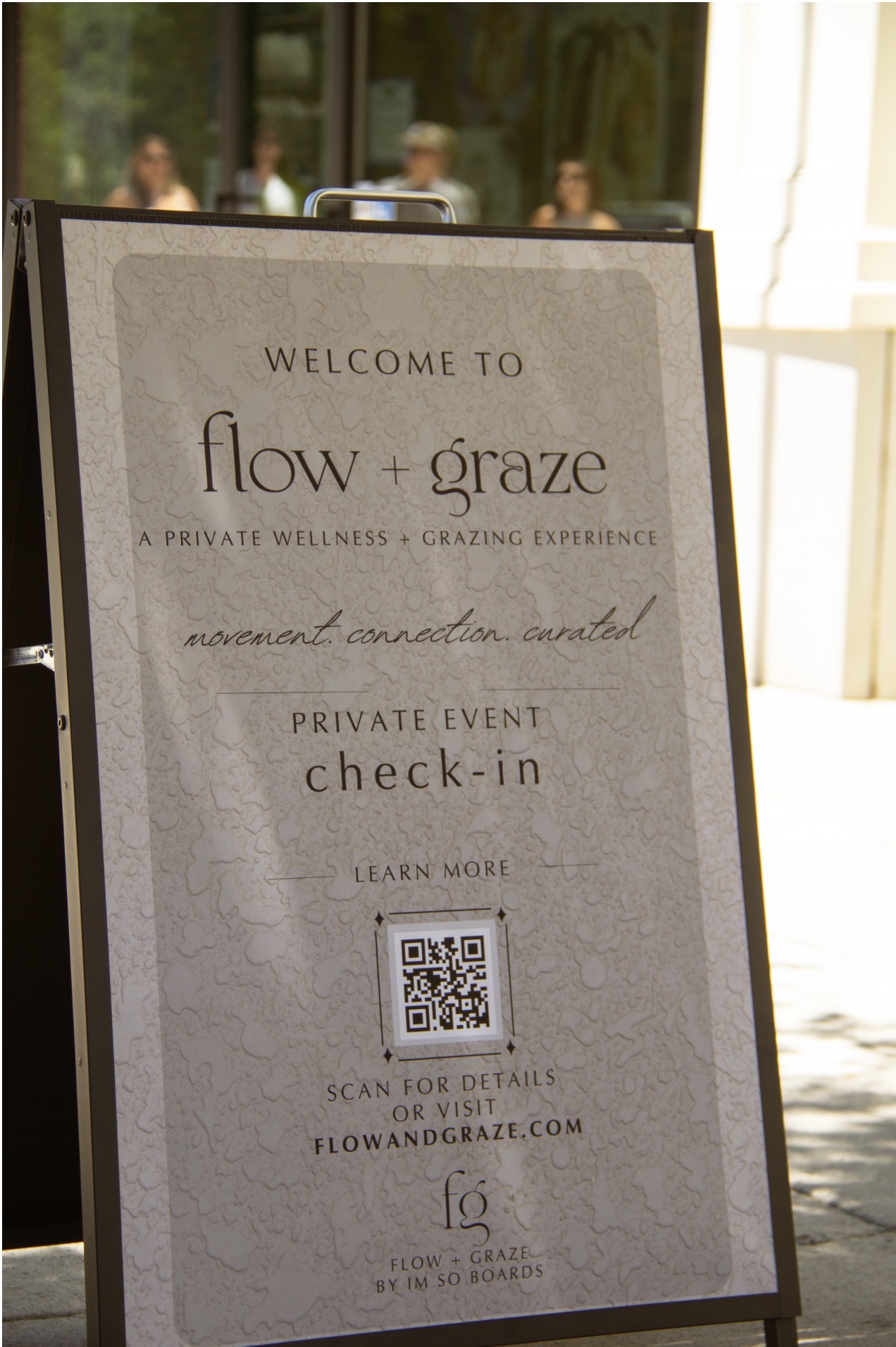 Signboard with text about wellness and private event, includes a QR code, in a bright indoor setting.