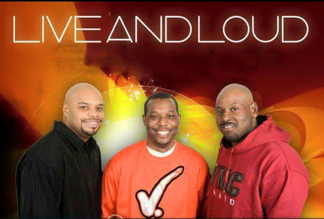 Three men smiling in front of a colorful background with the text 'LIVE AND LOUD'.