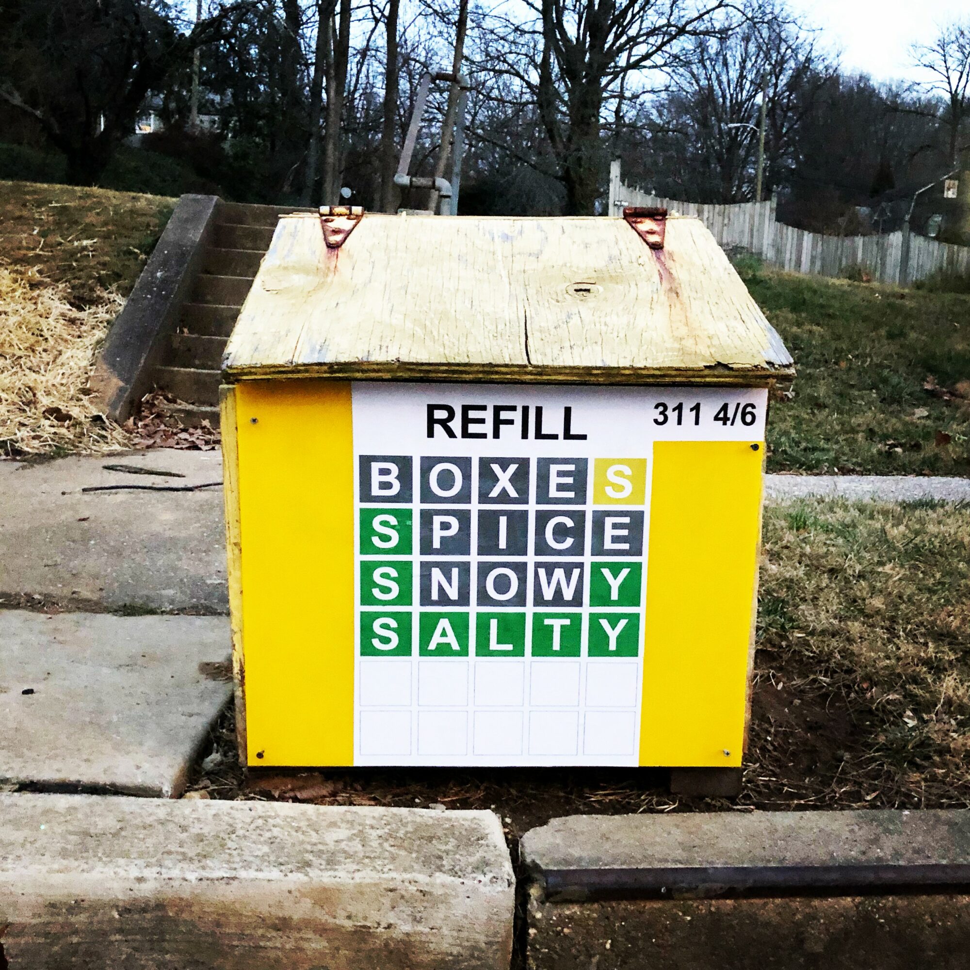 Recycling bin with a crossword puzzle design, containing words like box, spice, snow, salty, and yes, with a yellow background.