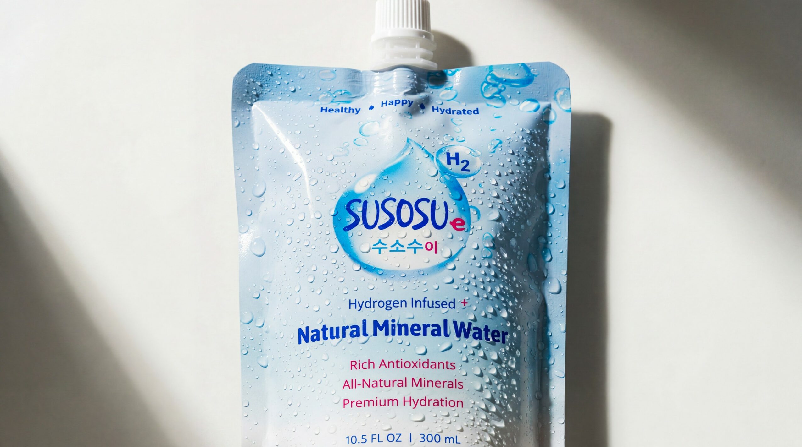 A blue and white pouch of Sususu hydrogen-infused natural mineral water with a spout, against a light background.