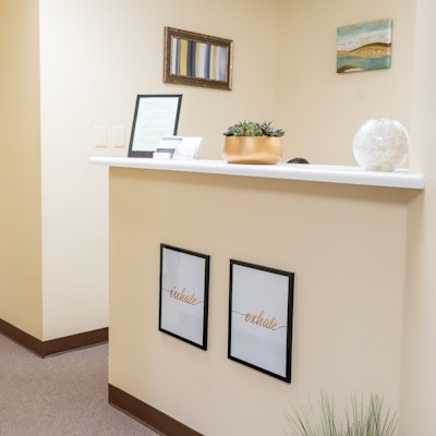 Reception area with framed artwork on wall, a counter with decorative items, and two framed pictures on the wall below.