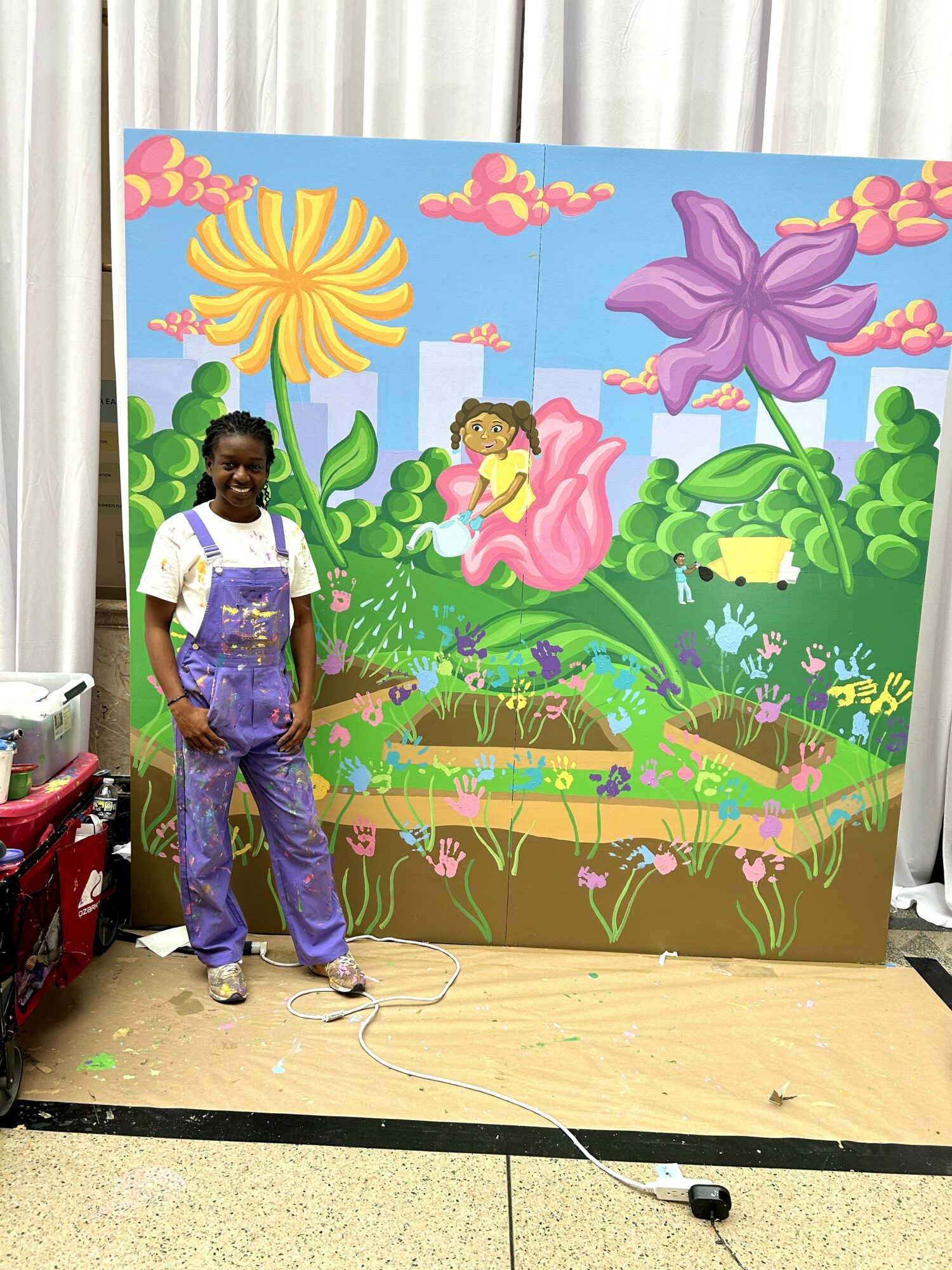 Child standing in front of a colorful, whimsical garden mural with large flowers and lush greenery.