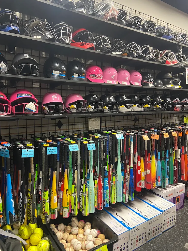 Display of helmets, golf clubs, and golf balls on shelves in a sporting goods store.