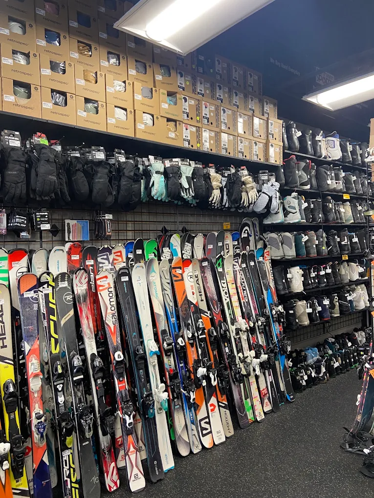 Ski equipment display with skis, helmets, and gear on shelves in a store.