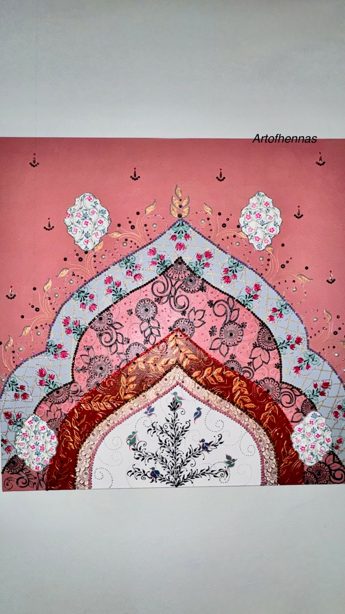 Decorative wall hanging with colorful patterns and floral designs, featuring arches and small hanging ornaments.