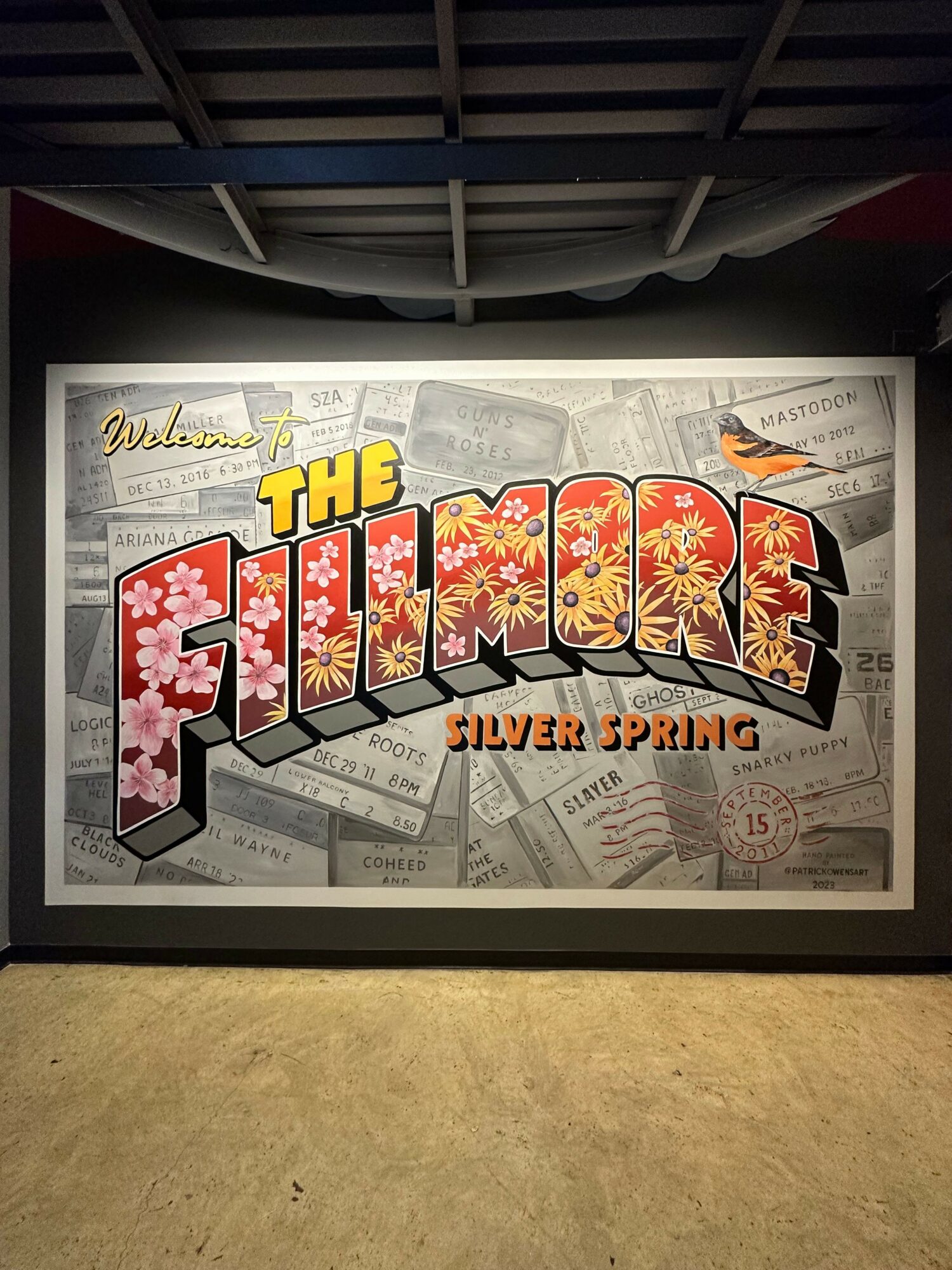 Framed poster with colorful text reading 'The Lottery' and 'Queen's Ransom' on a wall, with a gray and beige background.