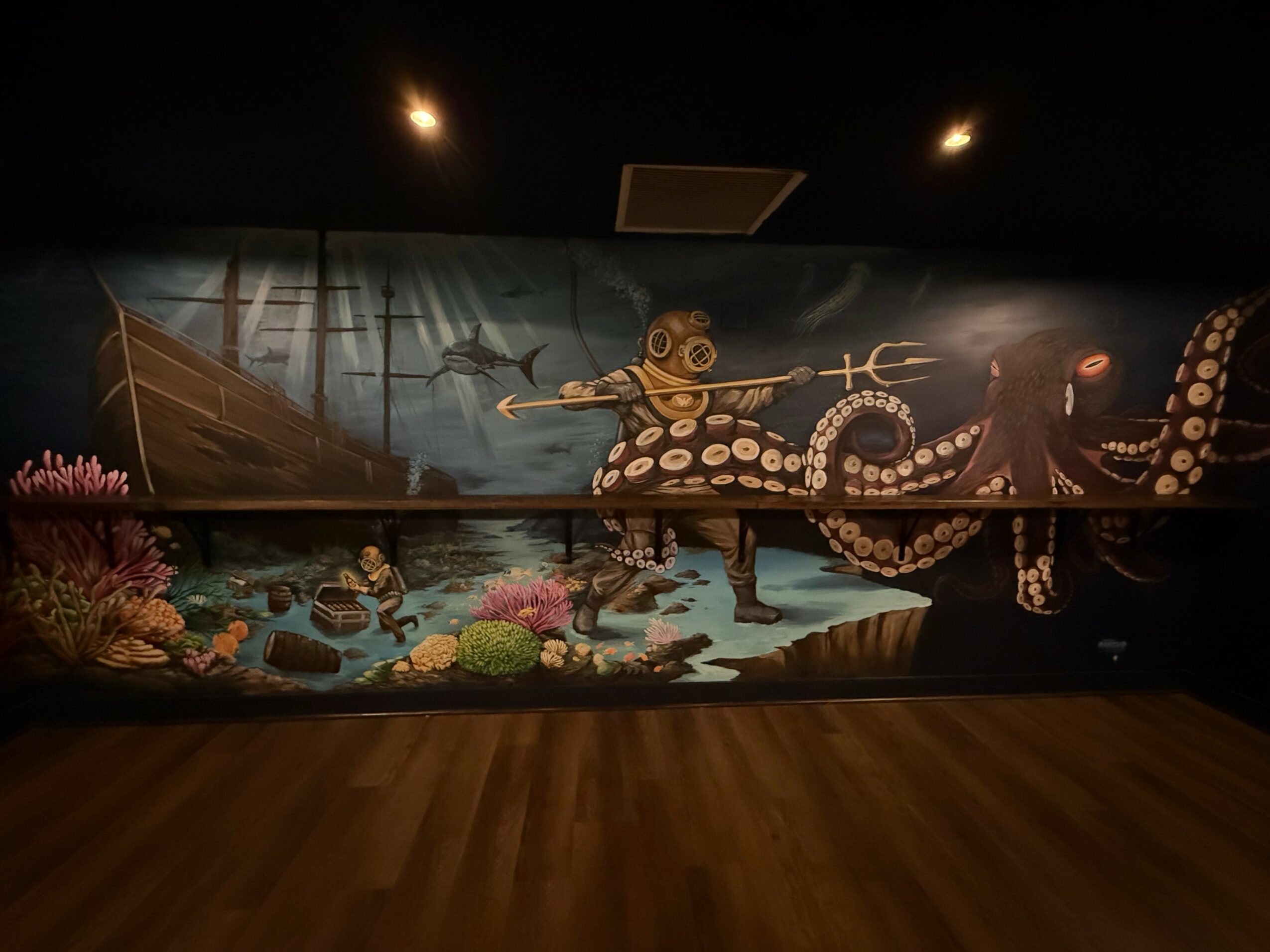 Underwater scene with a large octopus, a diver, and coral reef, painted on a wall mural.
